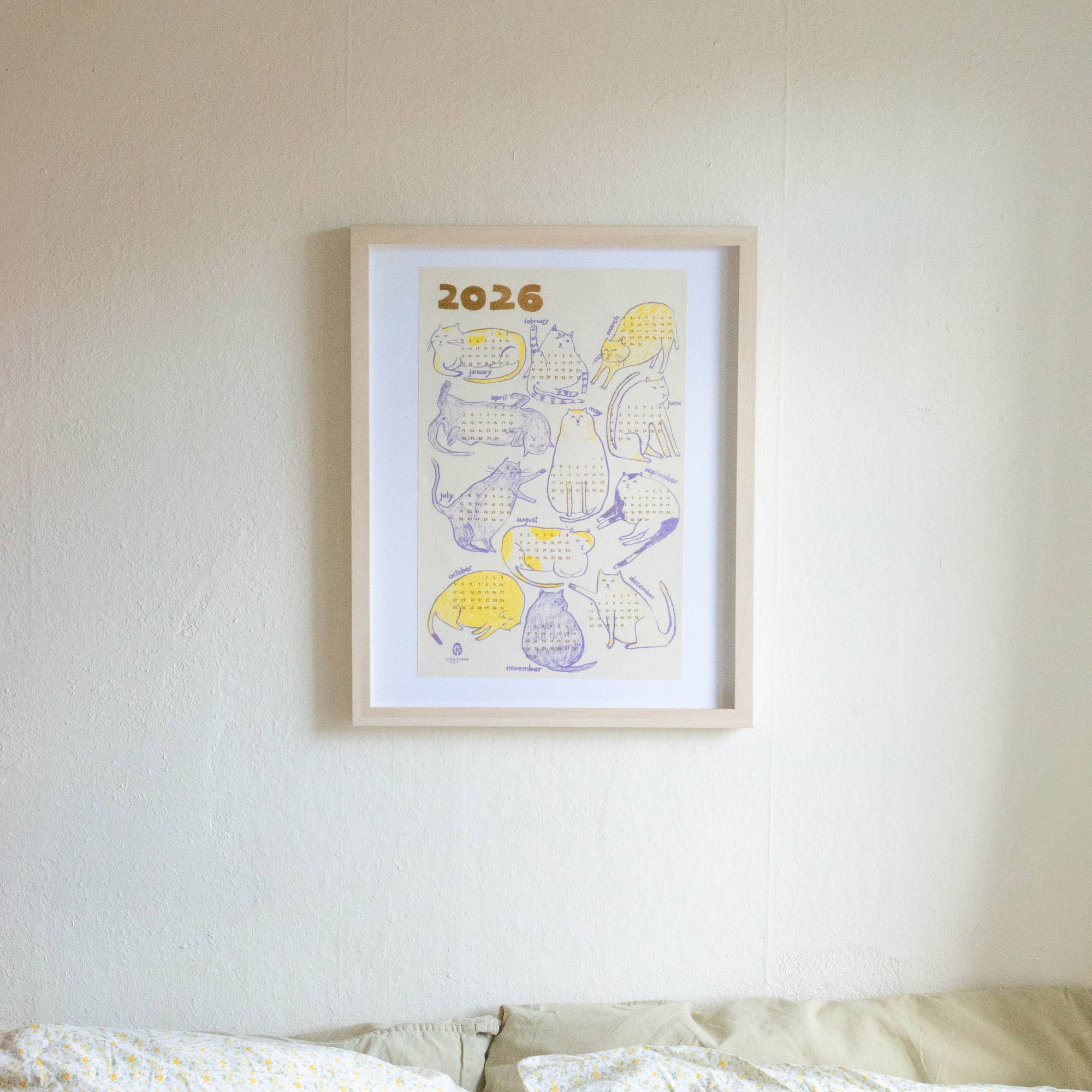 Framed artwork with '2026' on a white wall above a bed.