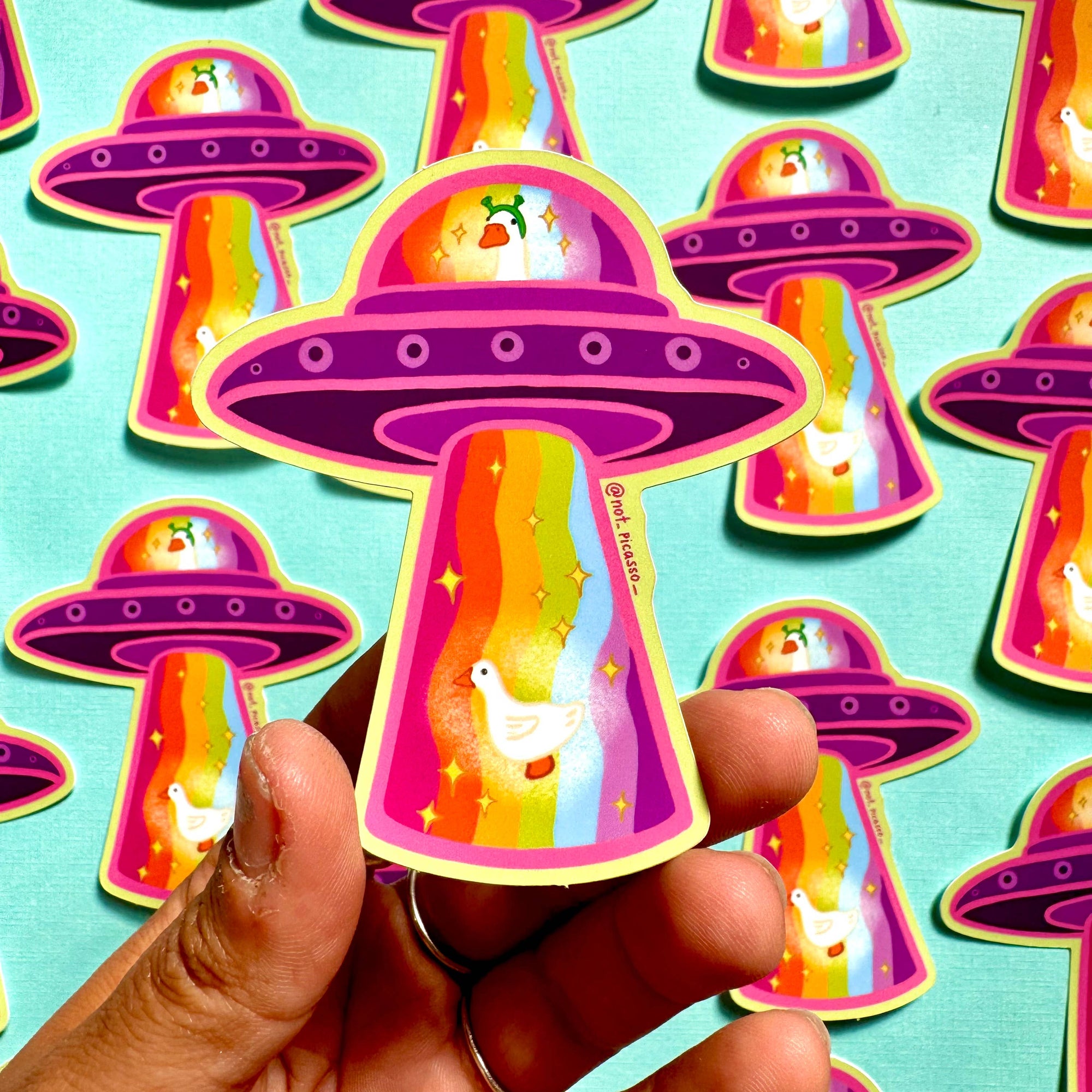 Colorful UFO stickers with a hand holding one against a patterned background