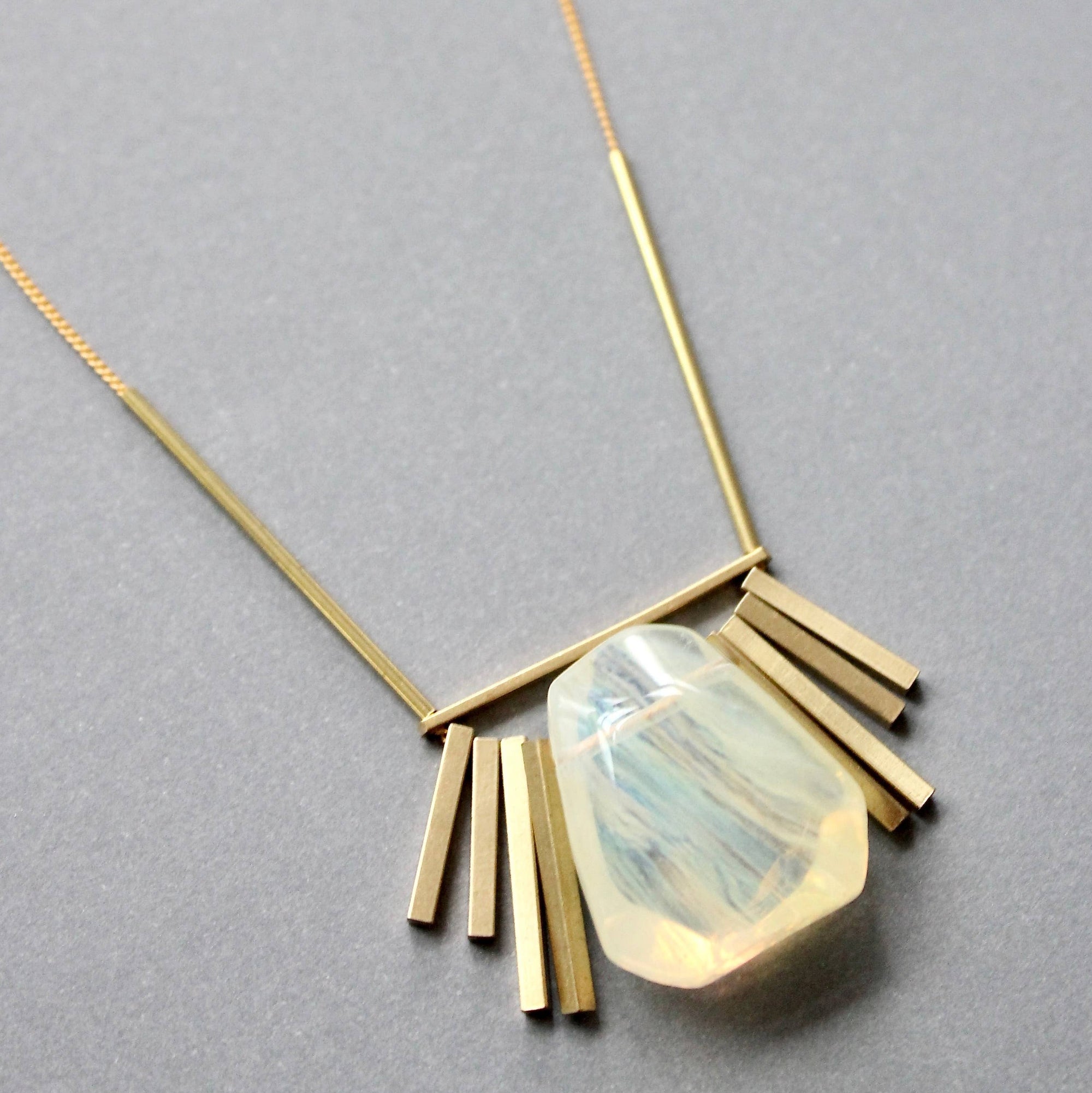 Gold necklace with a unique pendant on a gray background