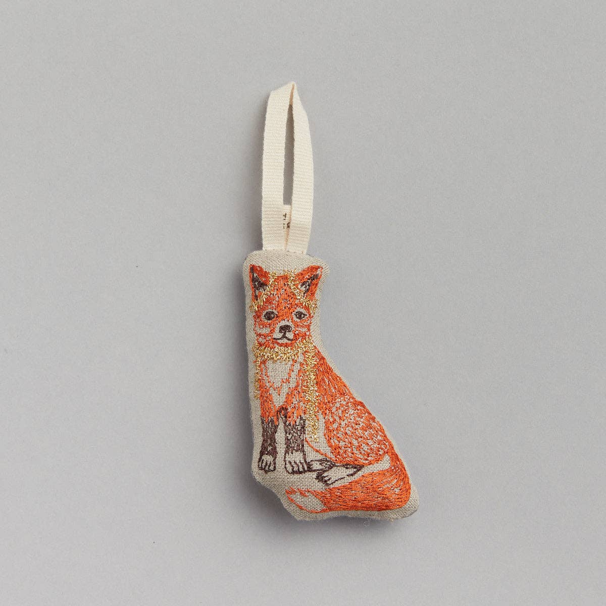 A fabric ornament in the shape of a fox with a tinsel-like pattern on it, designed to be hung on a Christmas tree.
