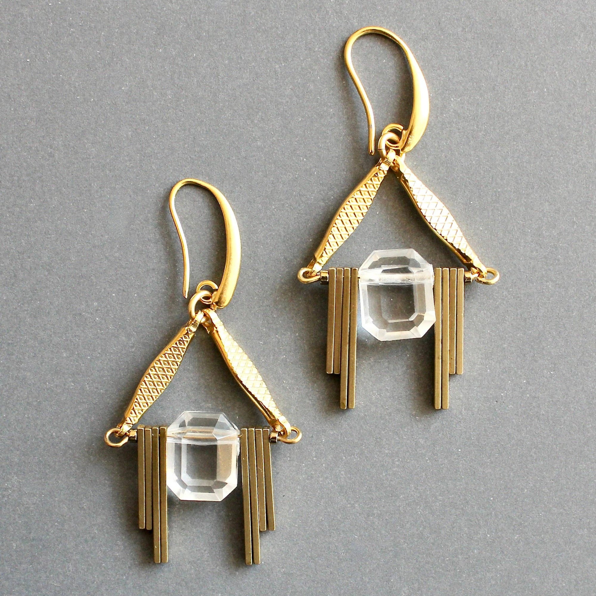 Gold earrings with clear crystal elements on a gray background