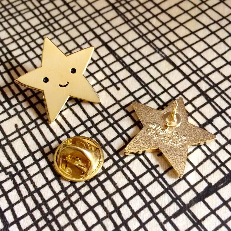 Gold star-shaped pins with a smiling face on a checkered background
