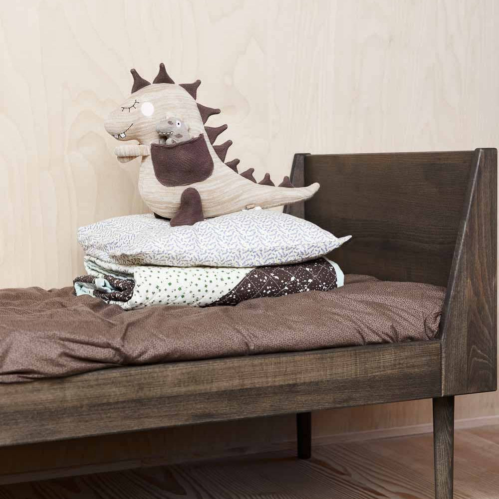 Wooden bed with dinosaur-themed pillows and bedding in a child's room.