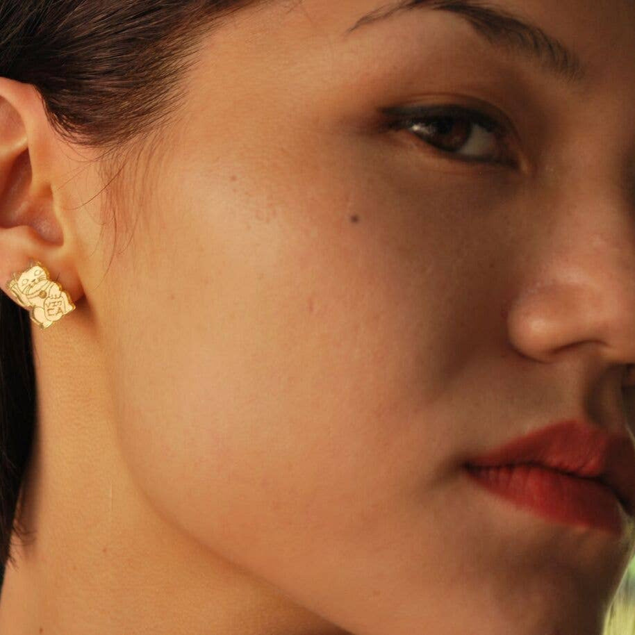 Close-up of a person wearing a gold earring with a dark background