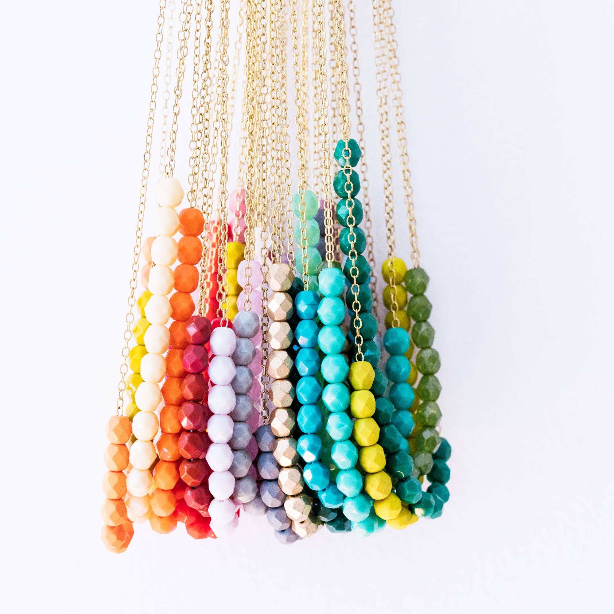 Colorful beaded necklaces on gold chains against a white background