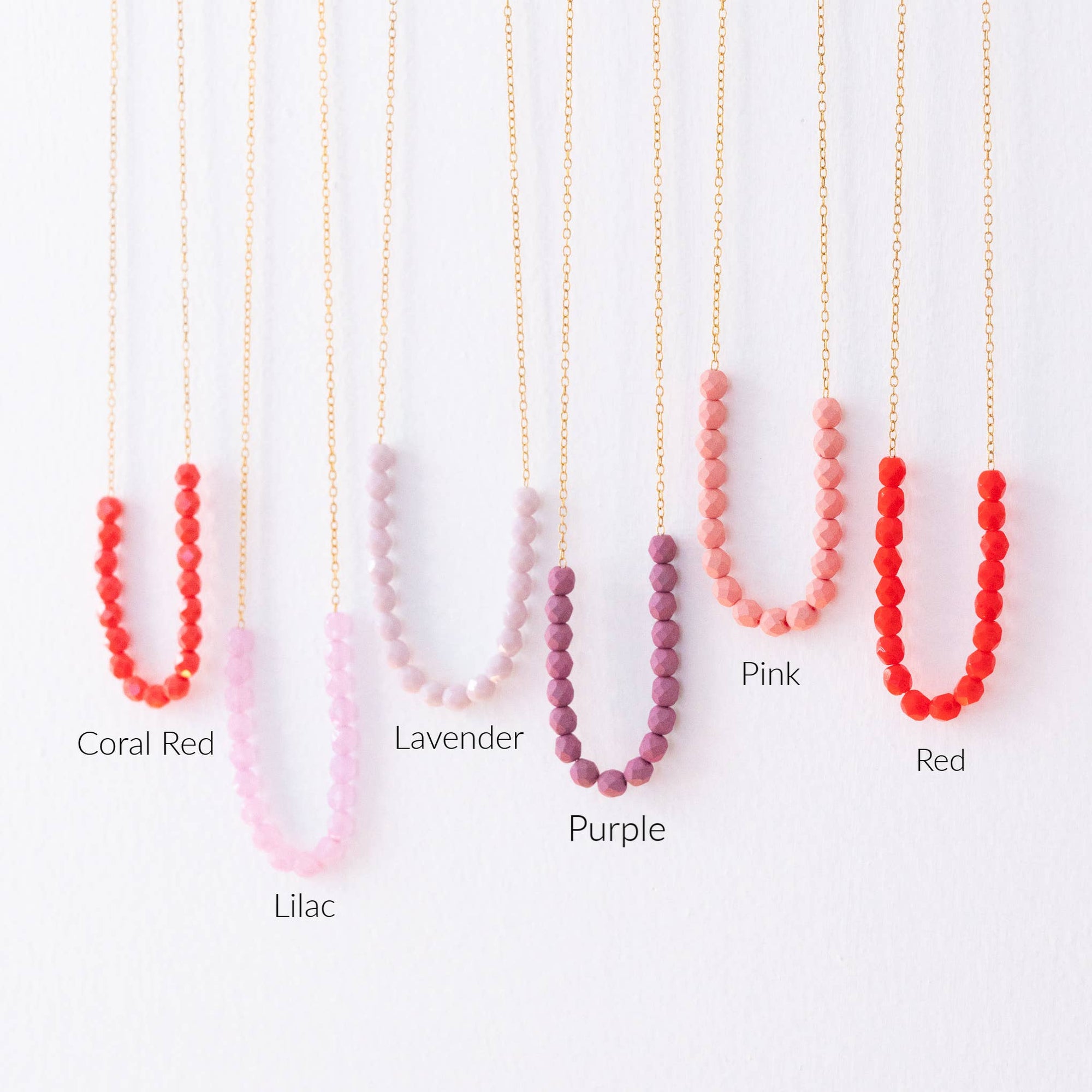 Set of four beaded necklaces in different colors on a white background