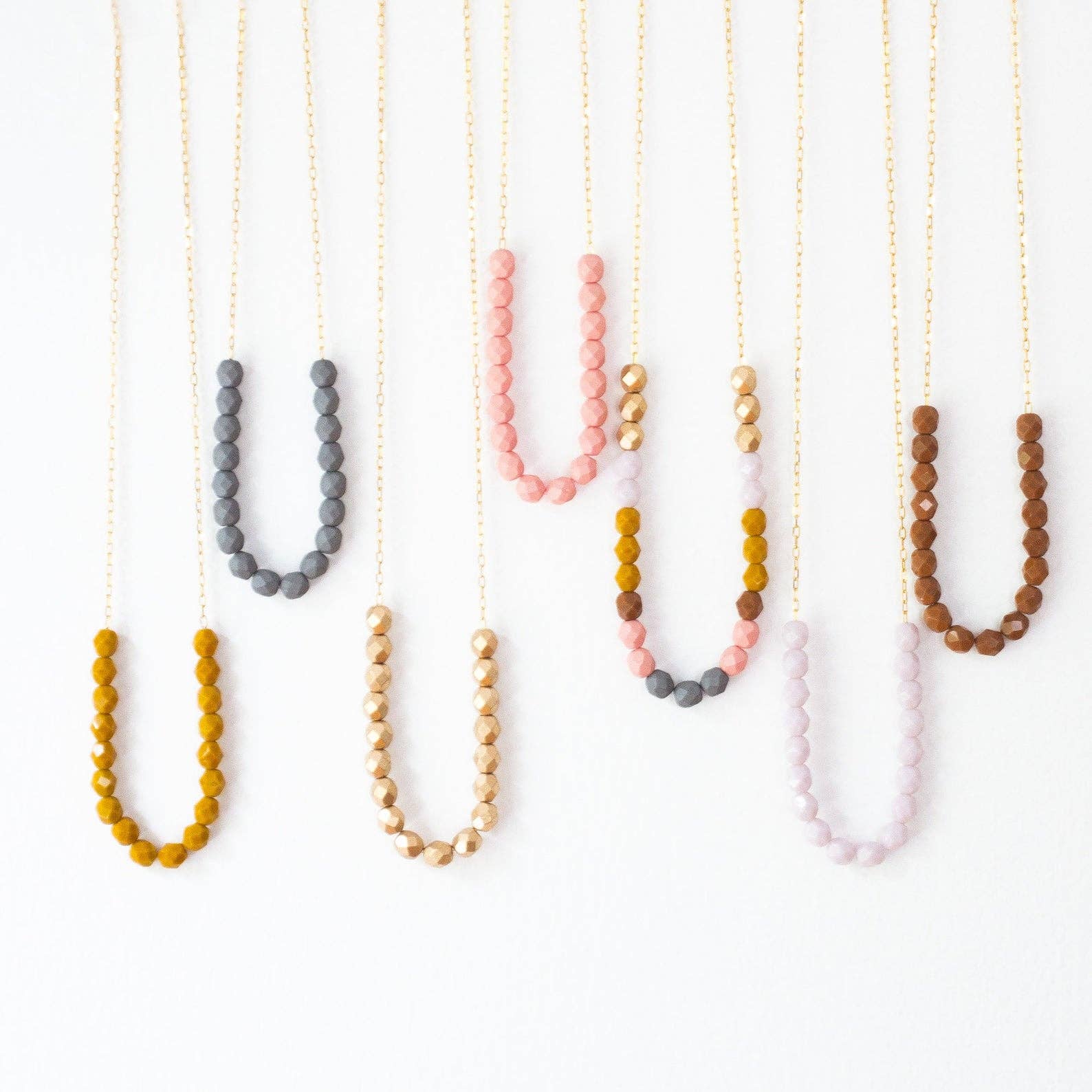 Set of beaded necklaces in various colors on a white background