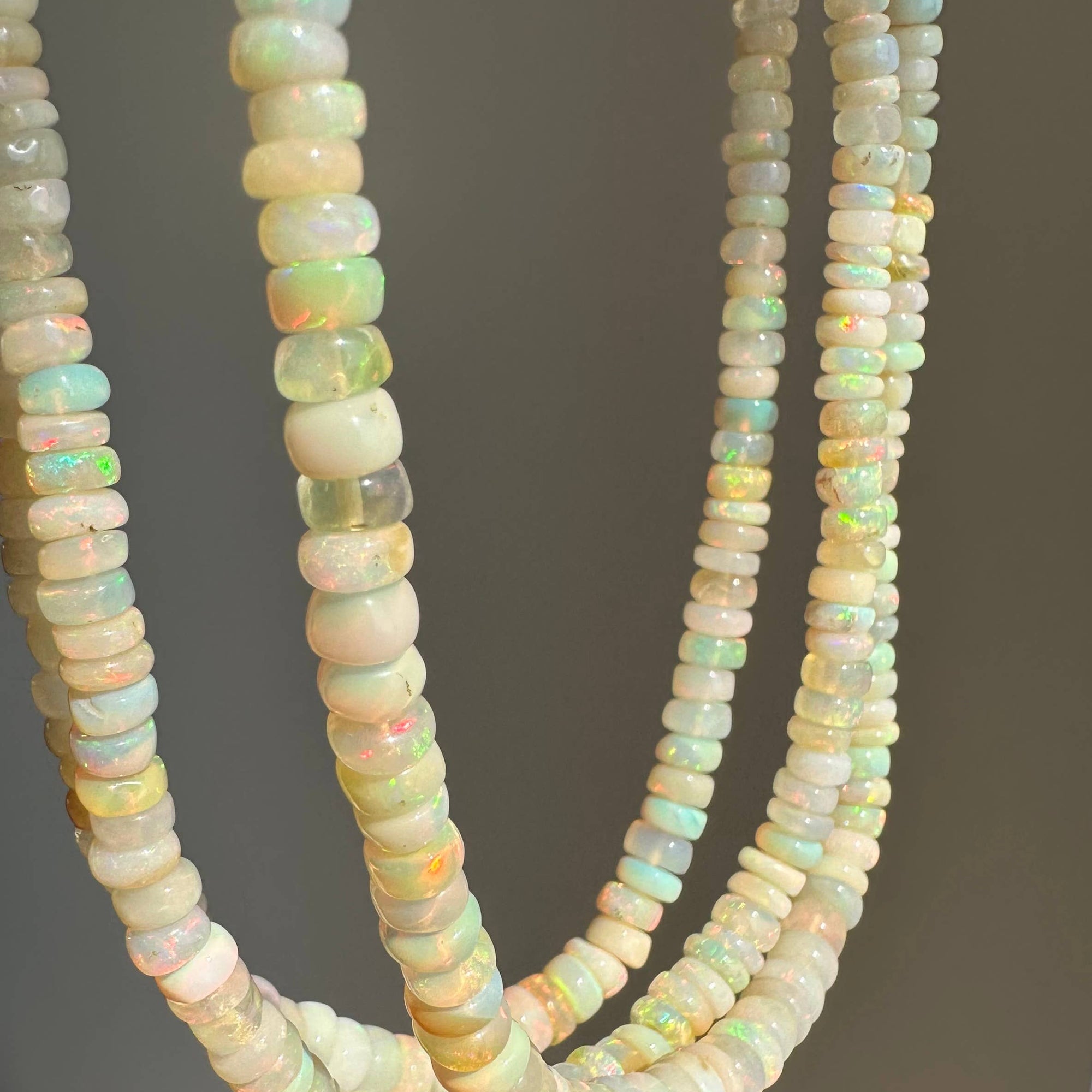 Three strands of opal beads on a gray background