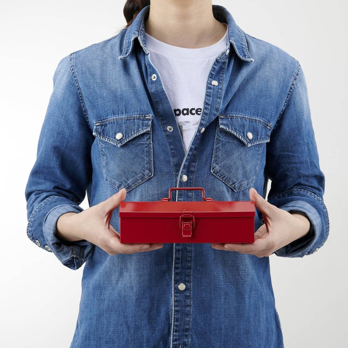 Person holding a red toolbox wearing a blue denim jacket on a white background