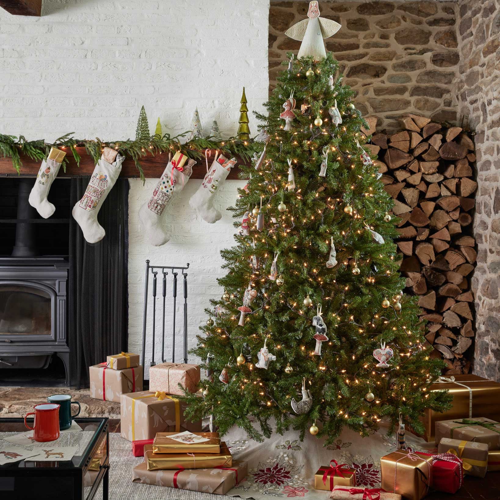 Decorated Christmas tree in a living room with stockings, presents, and a fireplace.