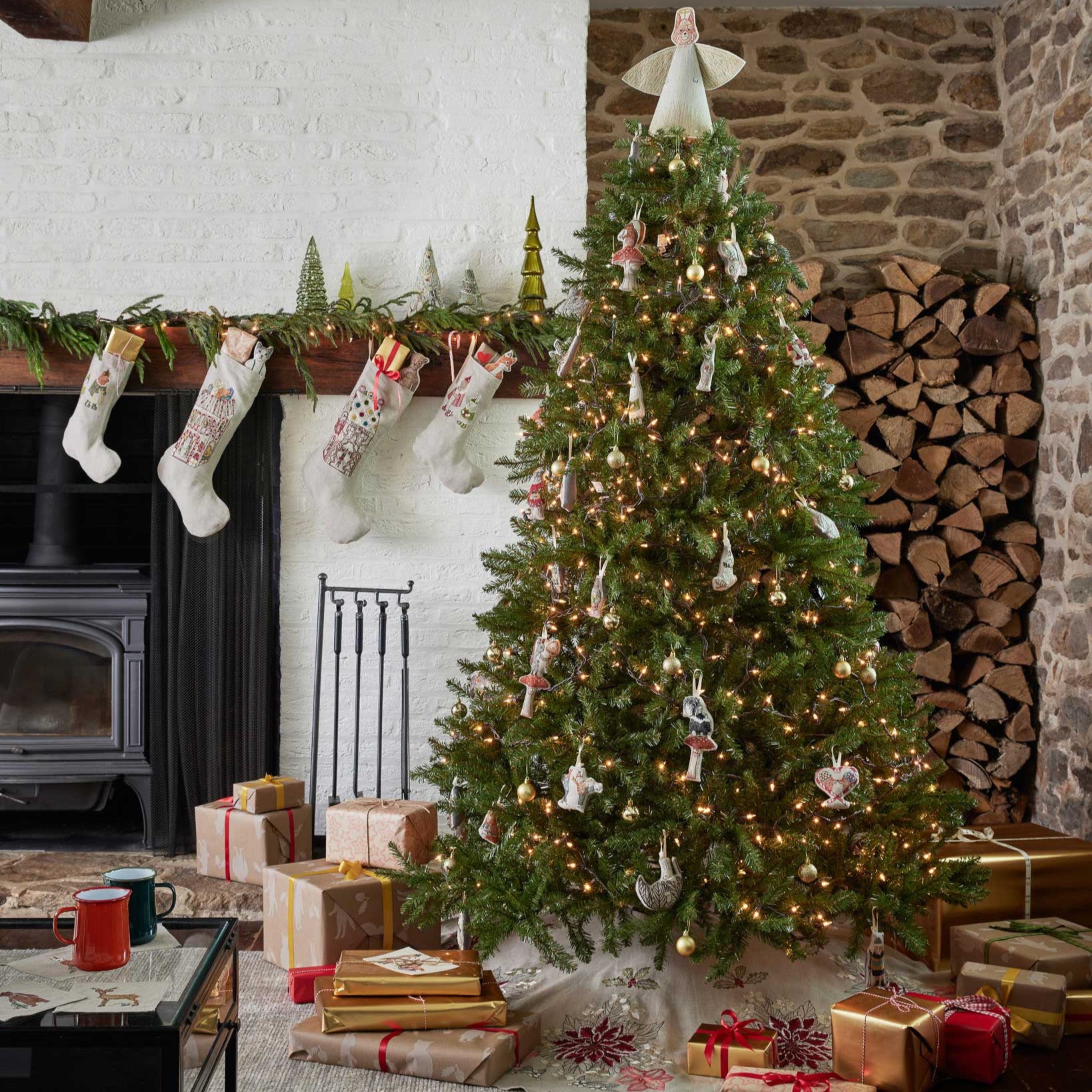 Decorated Christmas tree in a living room with stockings, presents, and a fireplace.