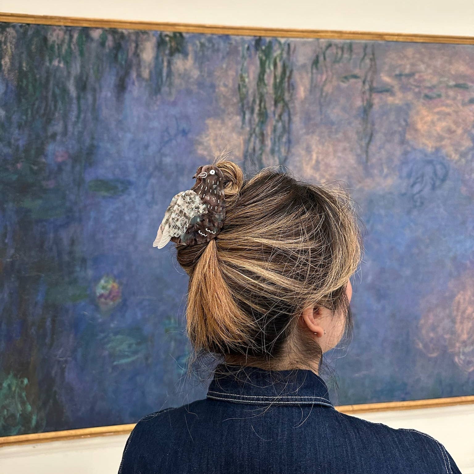 Person wearing a decorative hair clip in front of a painting