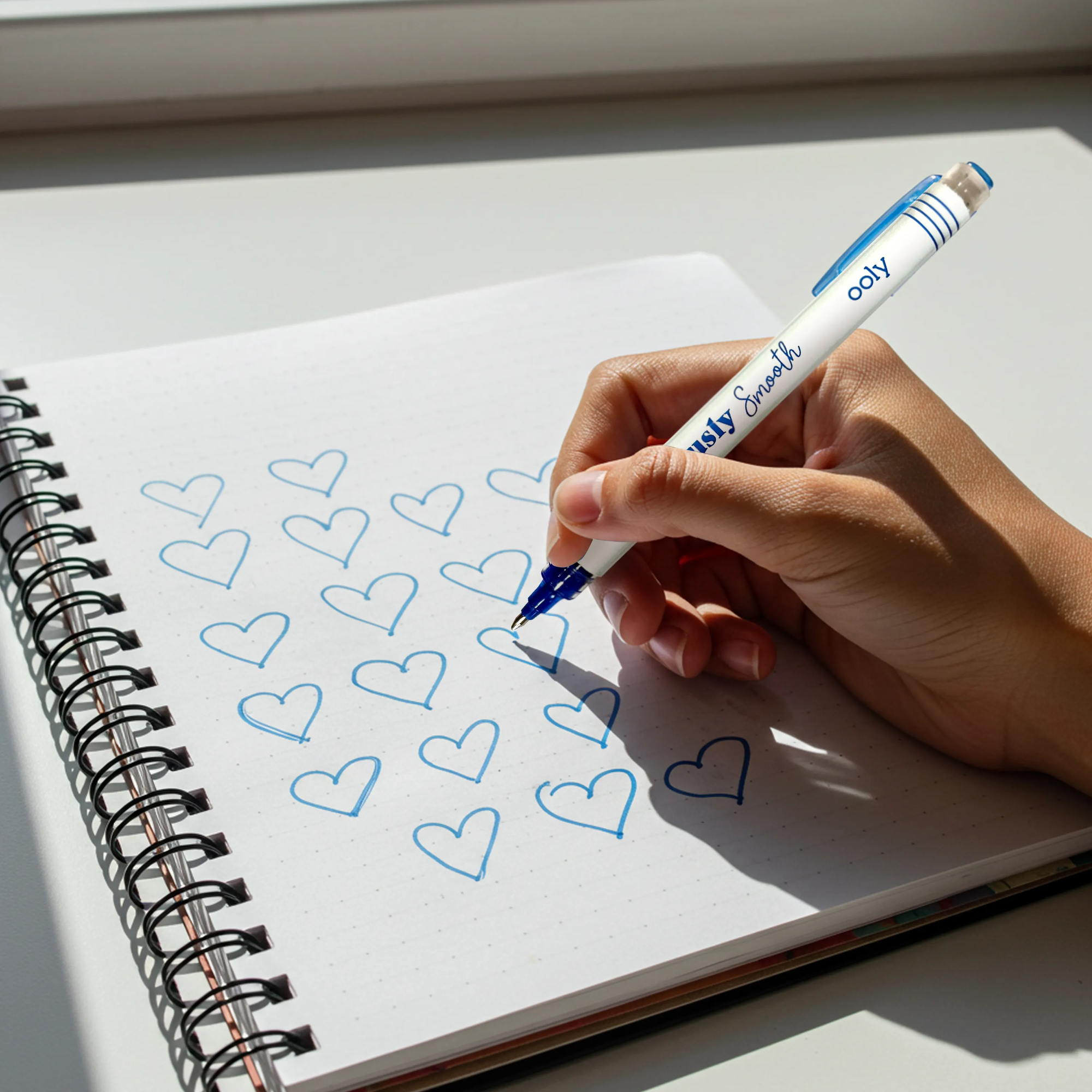 Hand drawing hearts in a notebook with a pen
