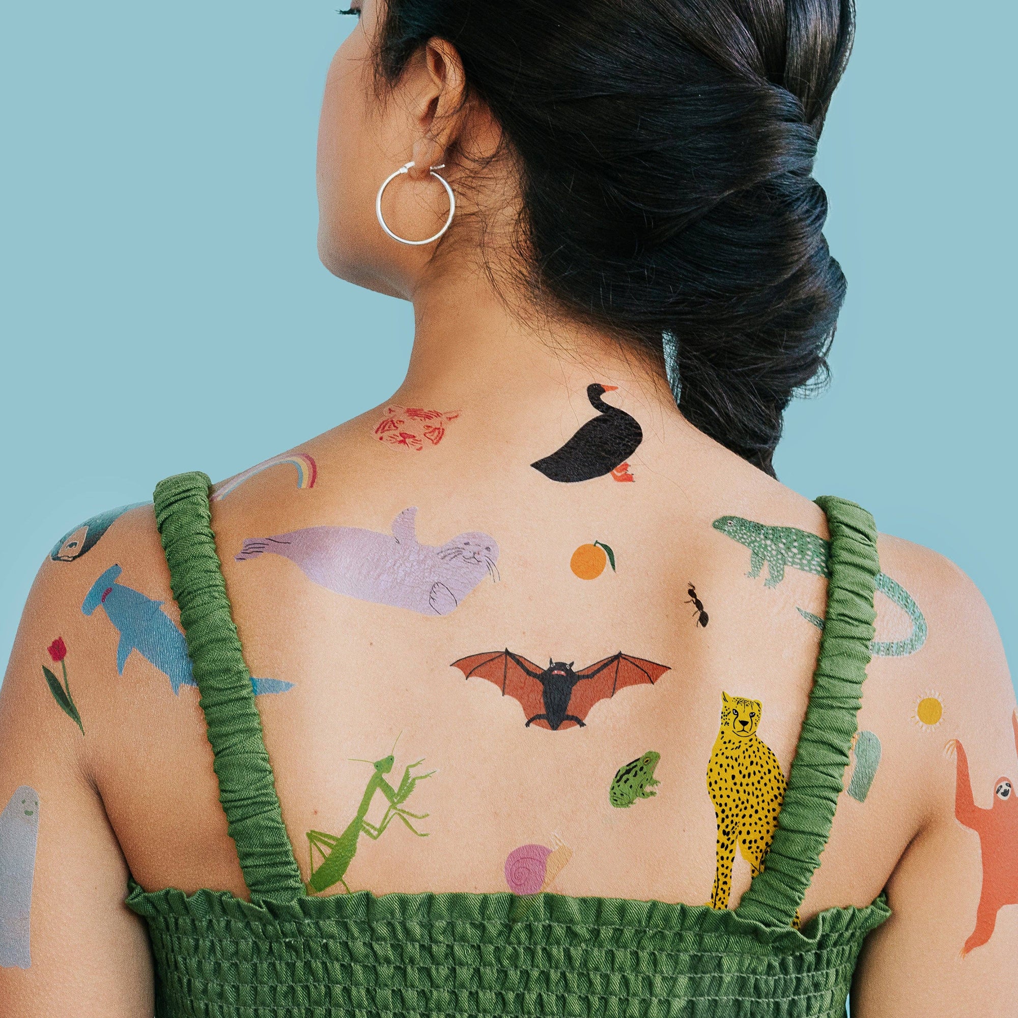 Person with colorful temporary tattoos on their back against a blue background