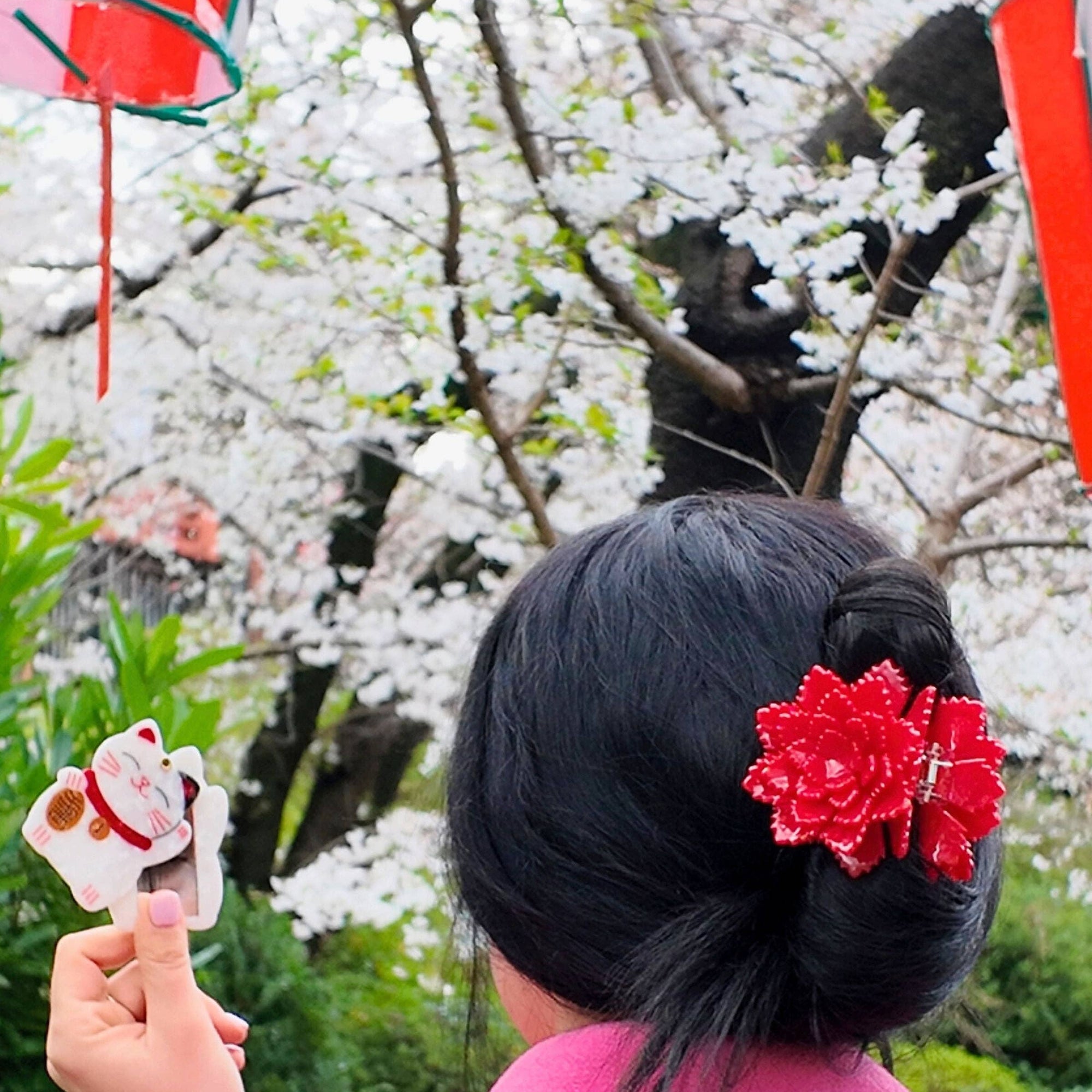 Person with a pink coat and floral hair accessory in front of cherry blossom trees