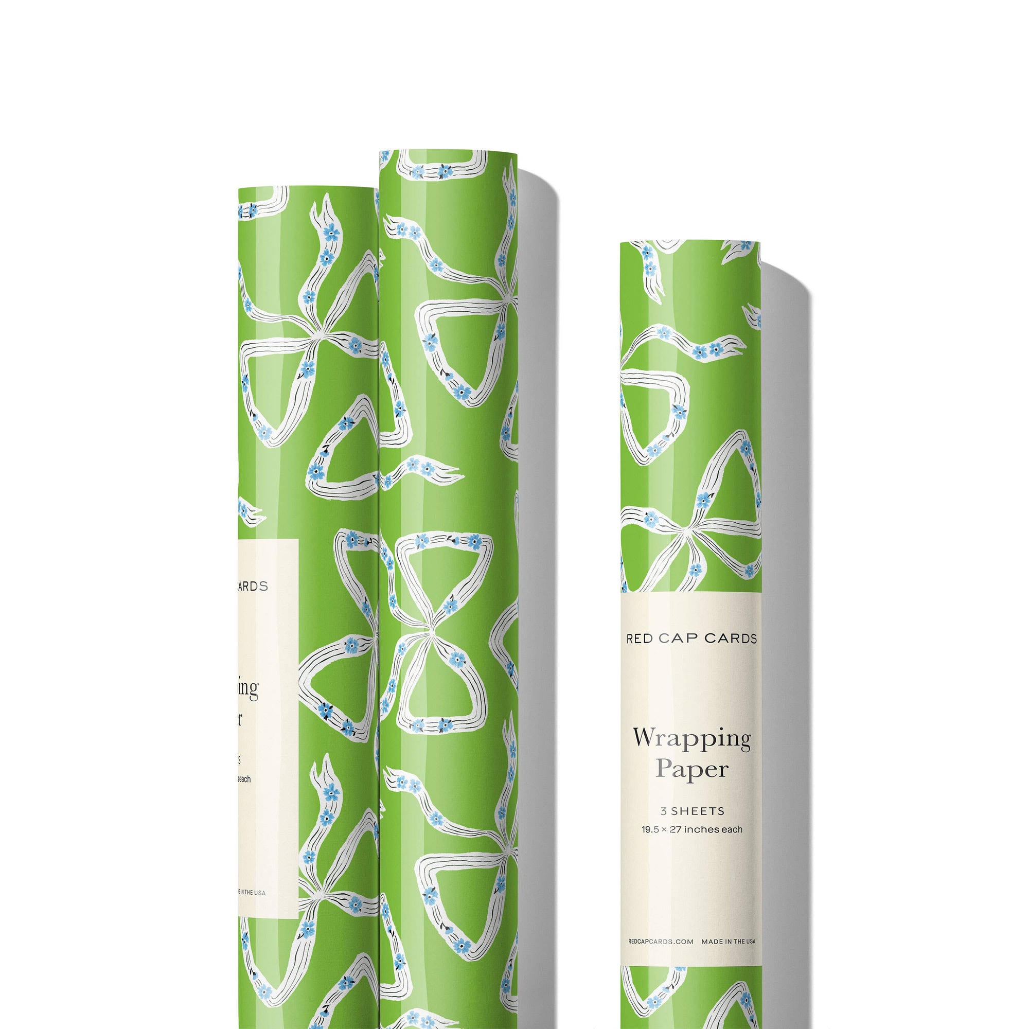 Two rolls of green wrapping paper with white patterns on a white background