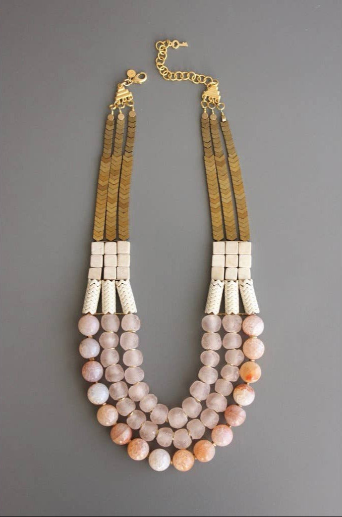 Multistrand beaded necklace with gold chain on a gray background
