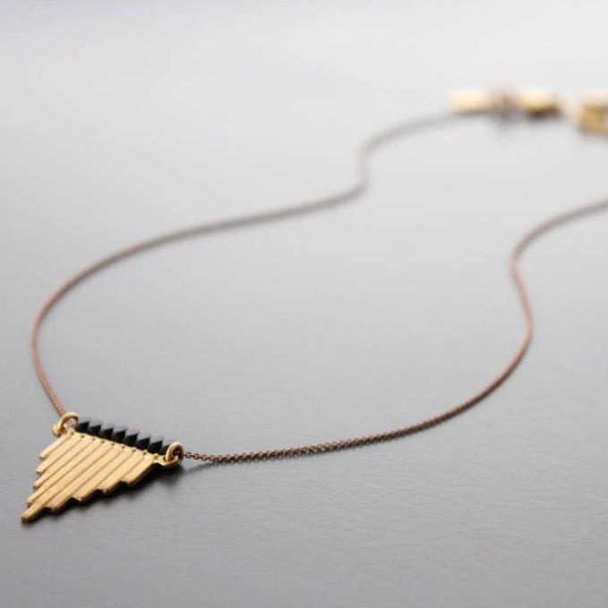 Necklace with a gold triangle pendant on a gray background