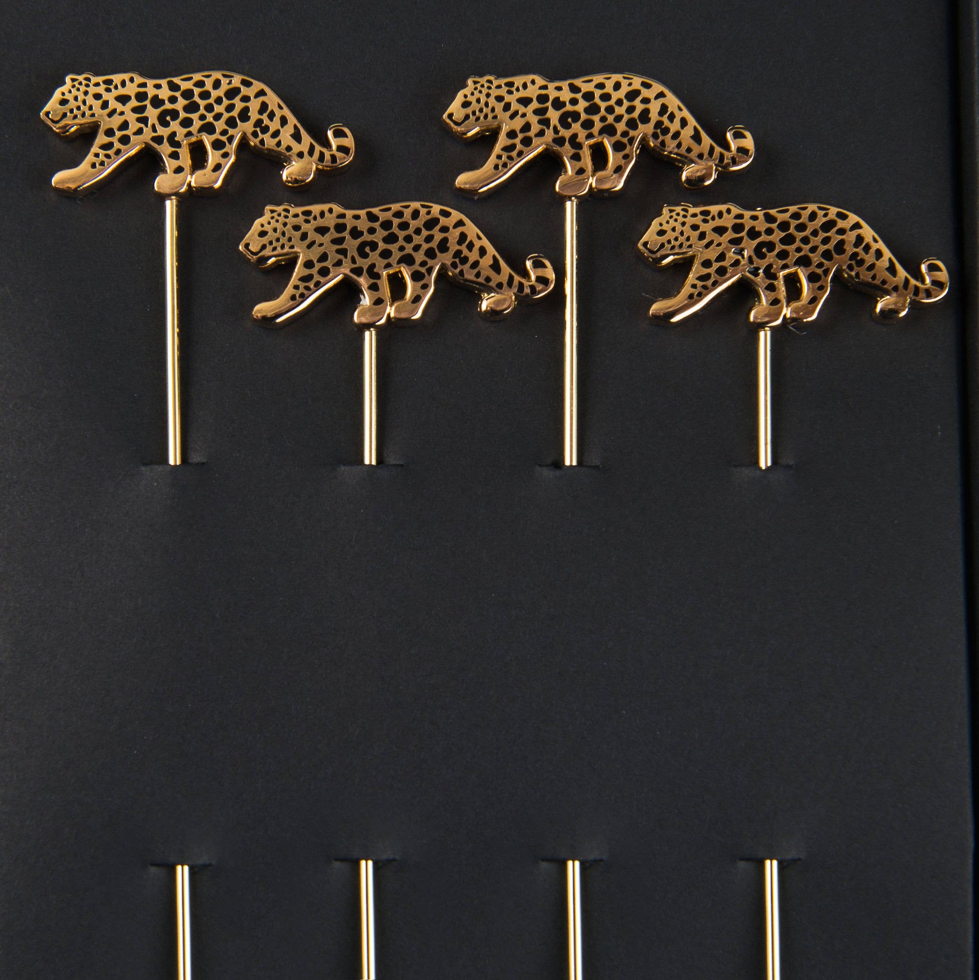 Four gold leopard figurines on black background
