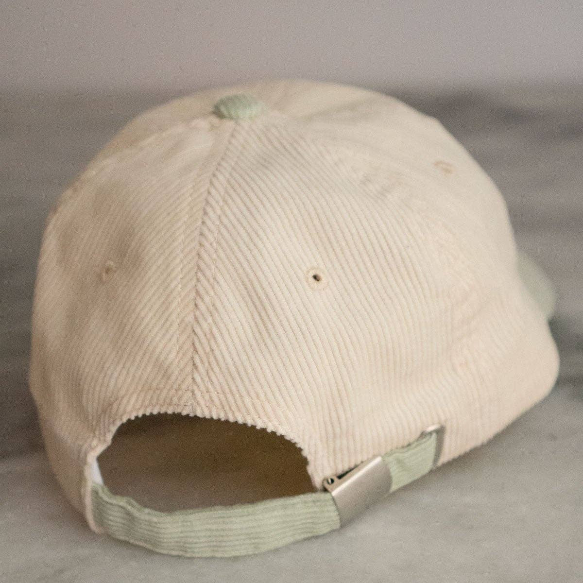 Beige cap with a broken bill on a gray surface