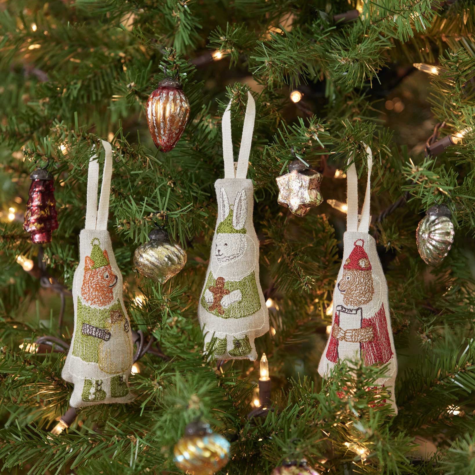 Decorative apron ornaments on a Christmas tree with lights and other decorations.