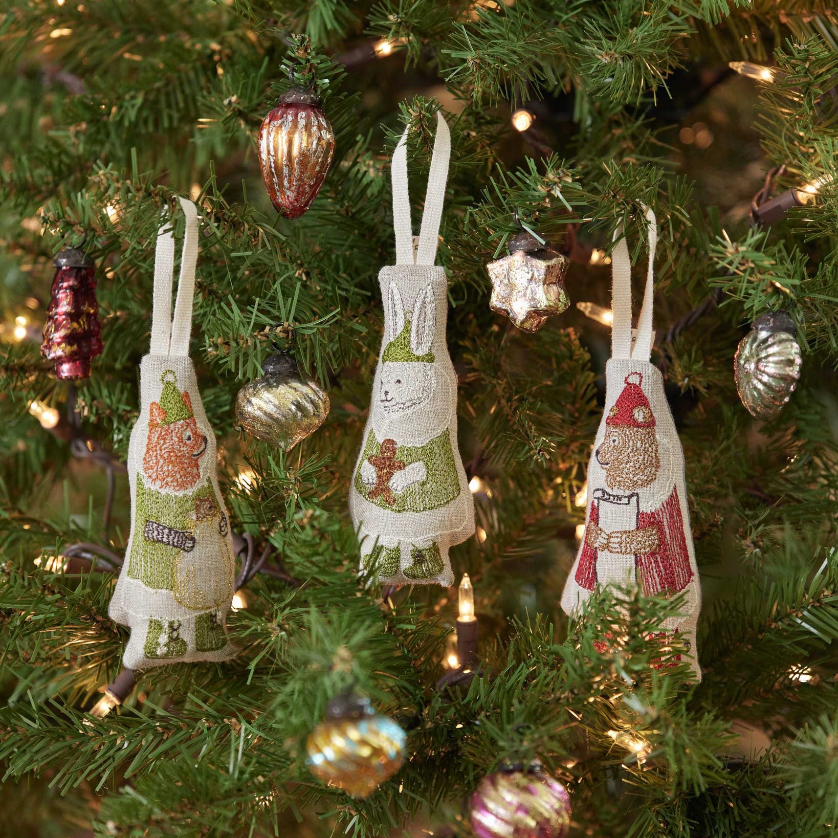 Decorative apron ornaments on a Christmas tree with lights and other decorations.