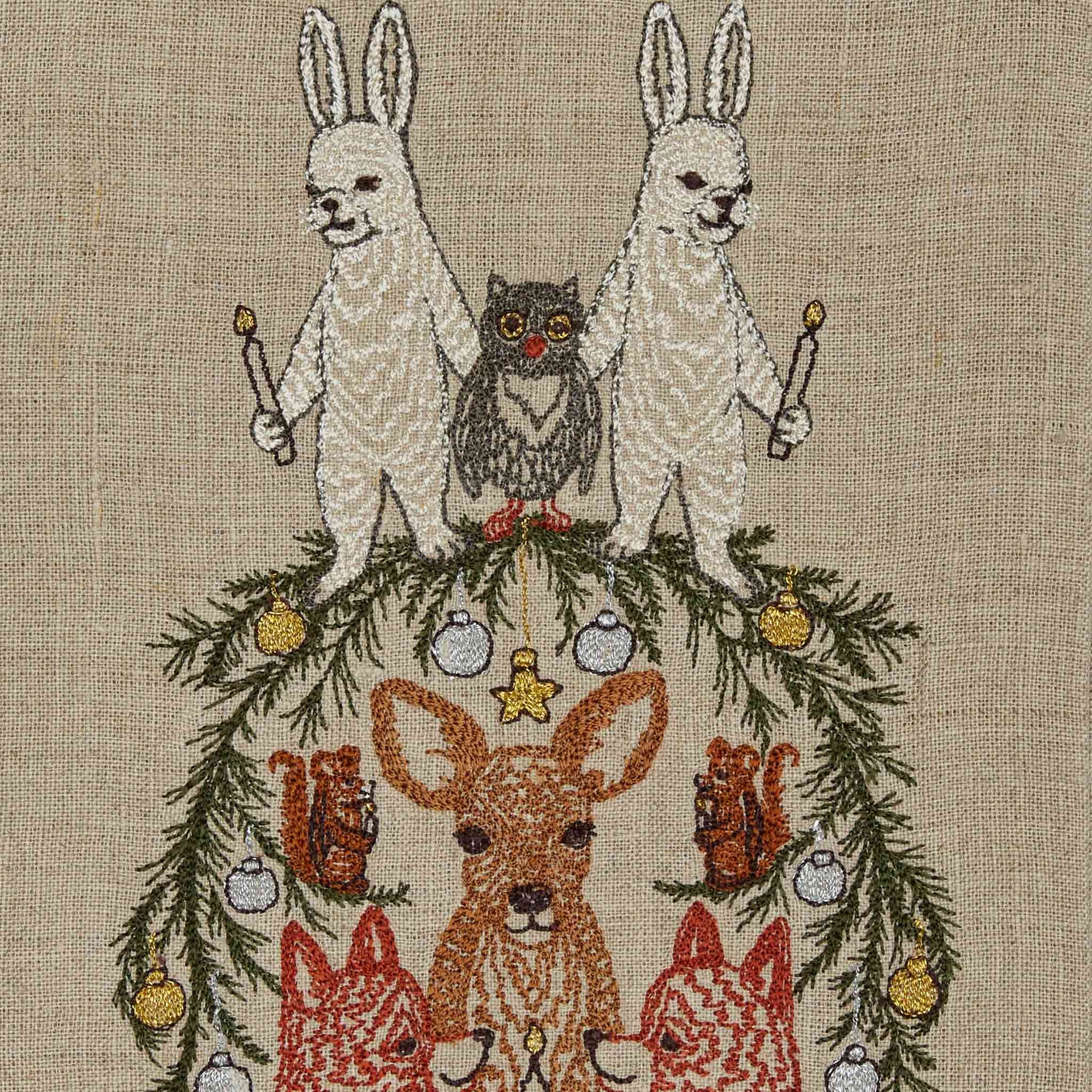 Embroidered design of animals on a Christmas tree with ornaments on a beige fabric background.