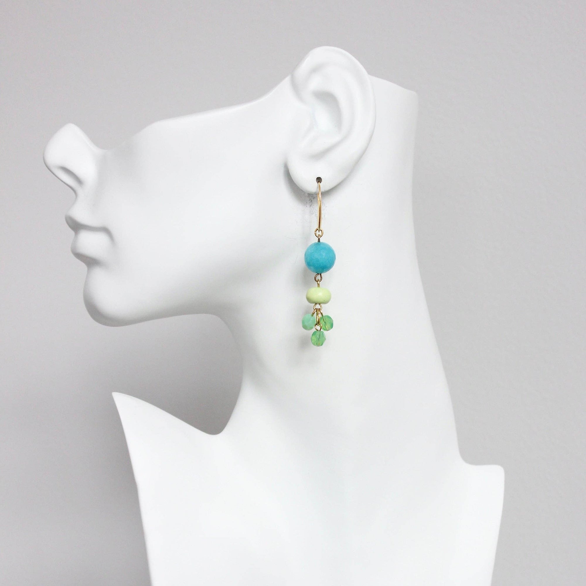 Earring on a mannequin ear with a gray background