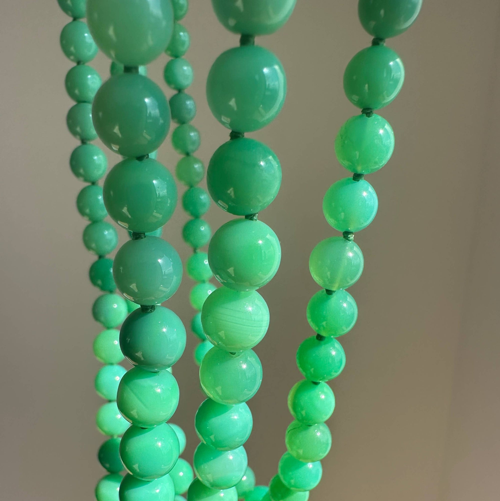 Green beaded necklace against a neutral background
