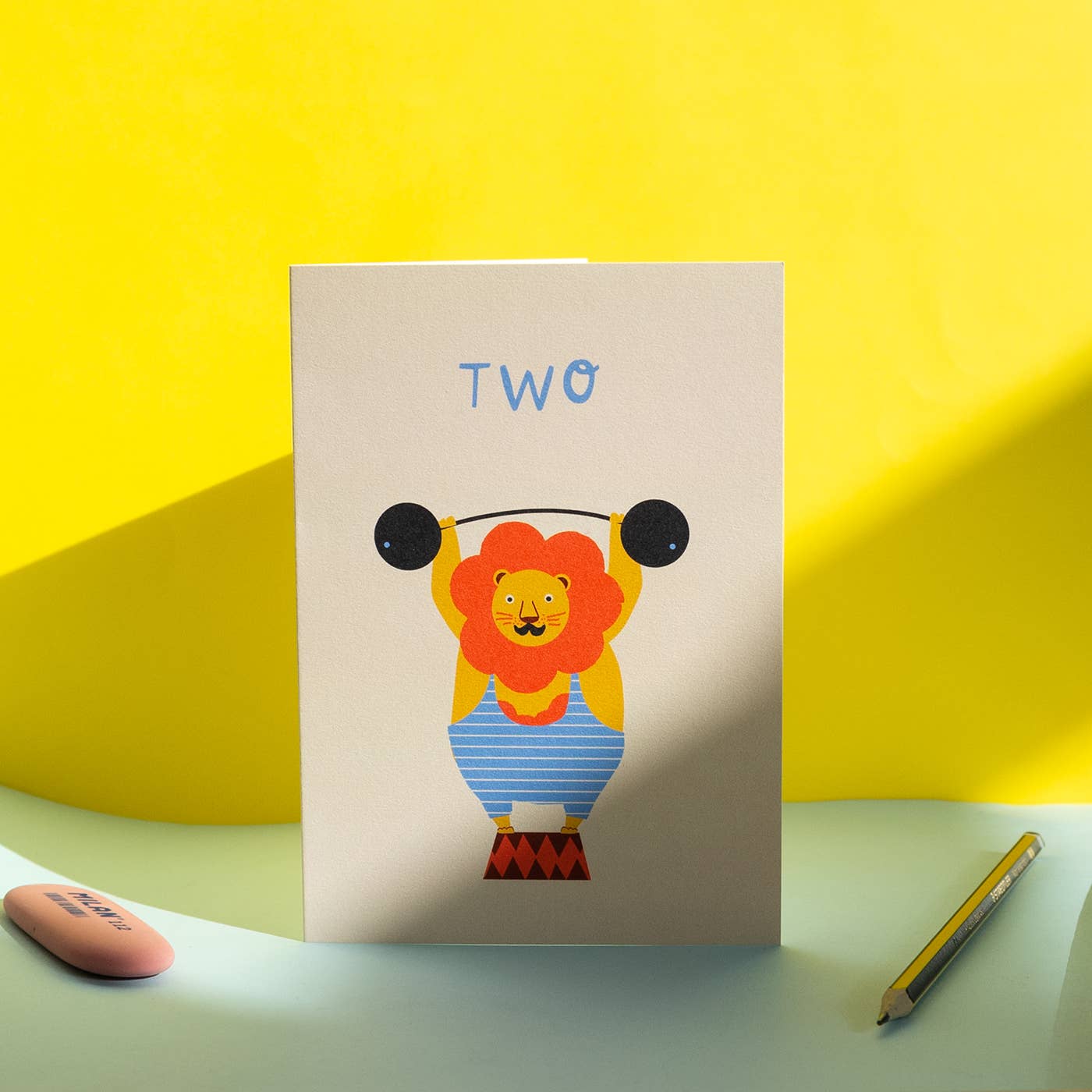card with a lion lifting weights illustration on a yellow background