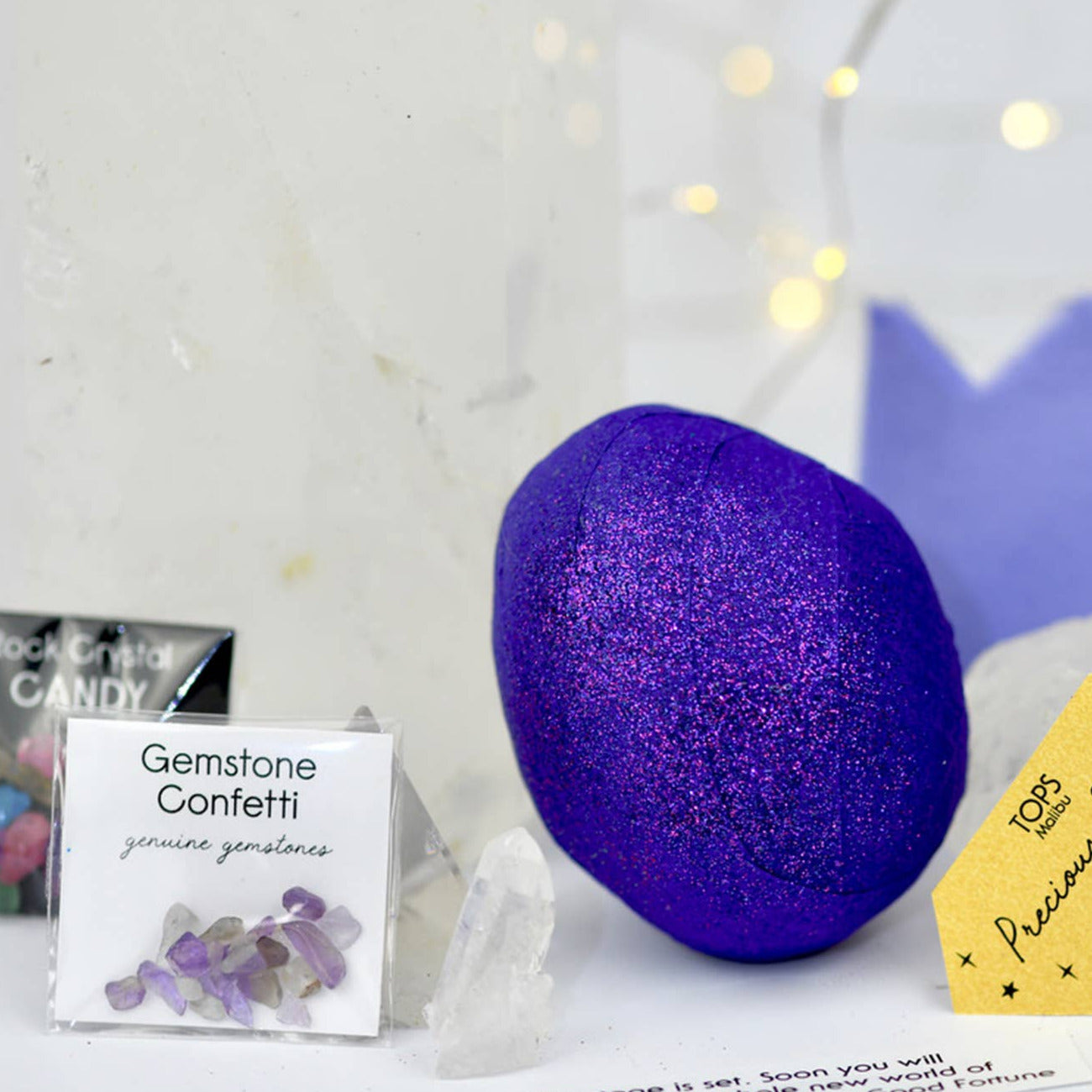Purple glittery surprise balls with a card and small bag on a white background