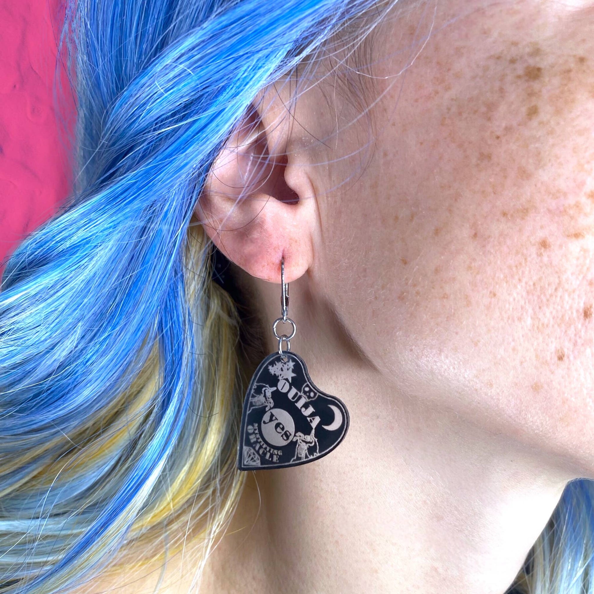Heart-shaped earrings worn by a person with blue hair