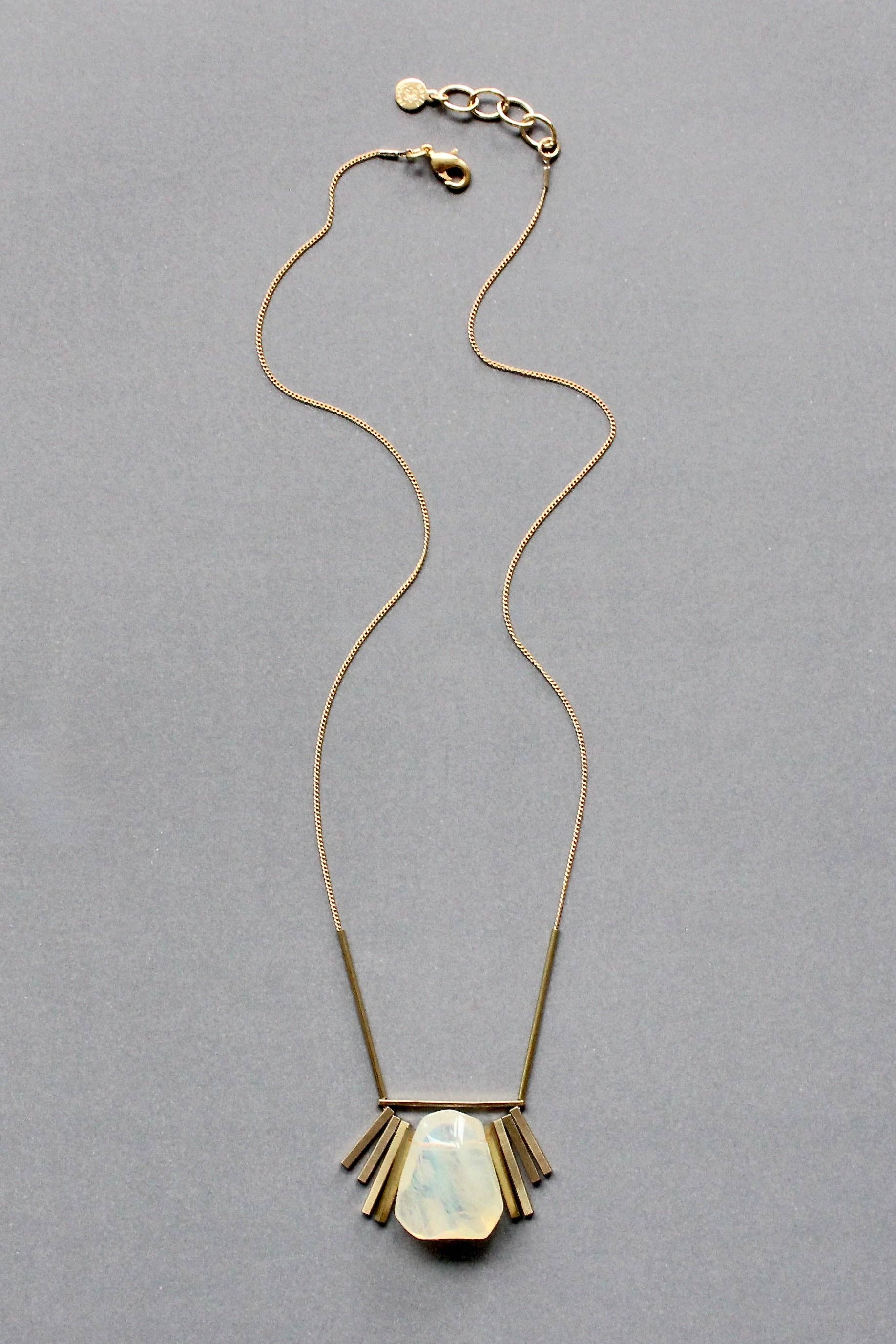 Necklace with a gold fringe pendant on a gray background