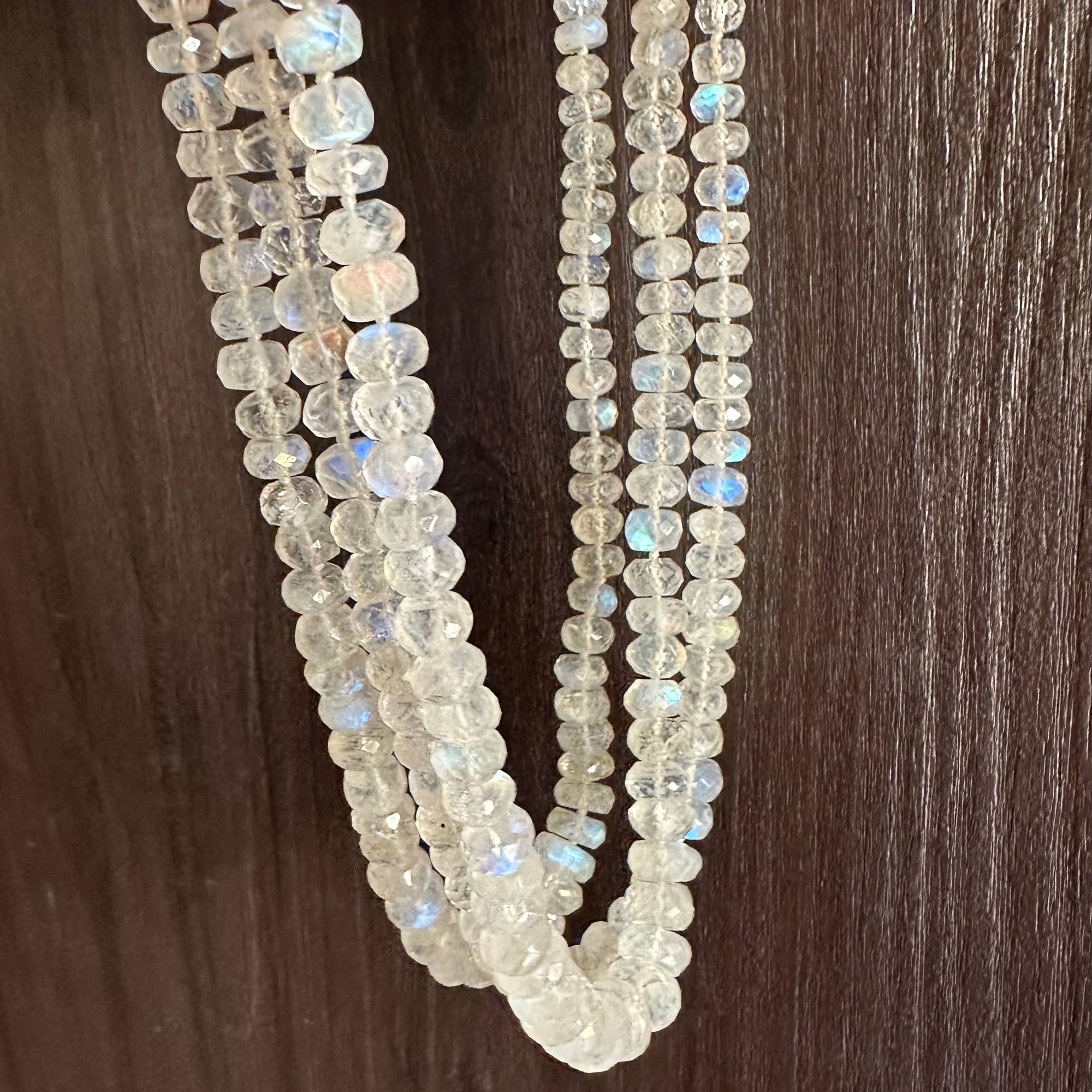Beaded necklace with rainbow moonstone-like stones on a wooden surface