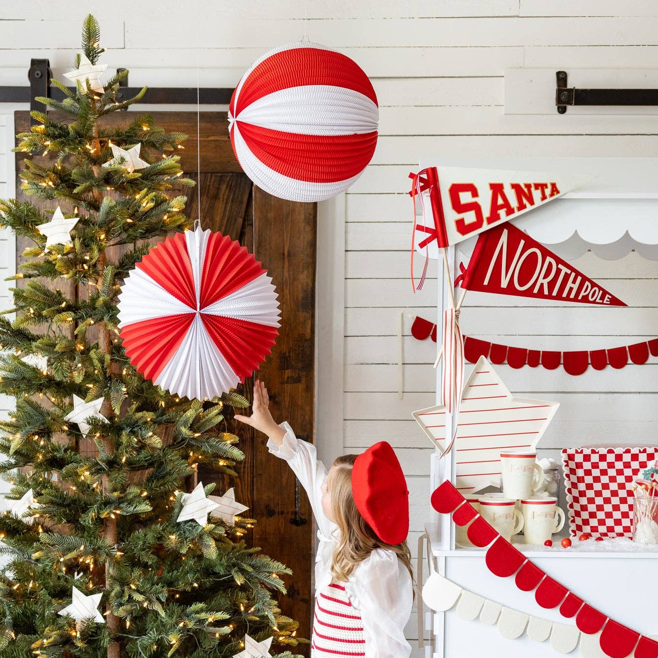 Child in festive outfit near a decorated Christmas tree with presents and holiday decorations.