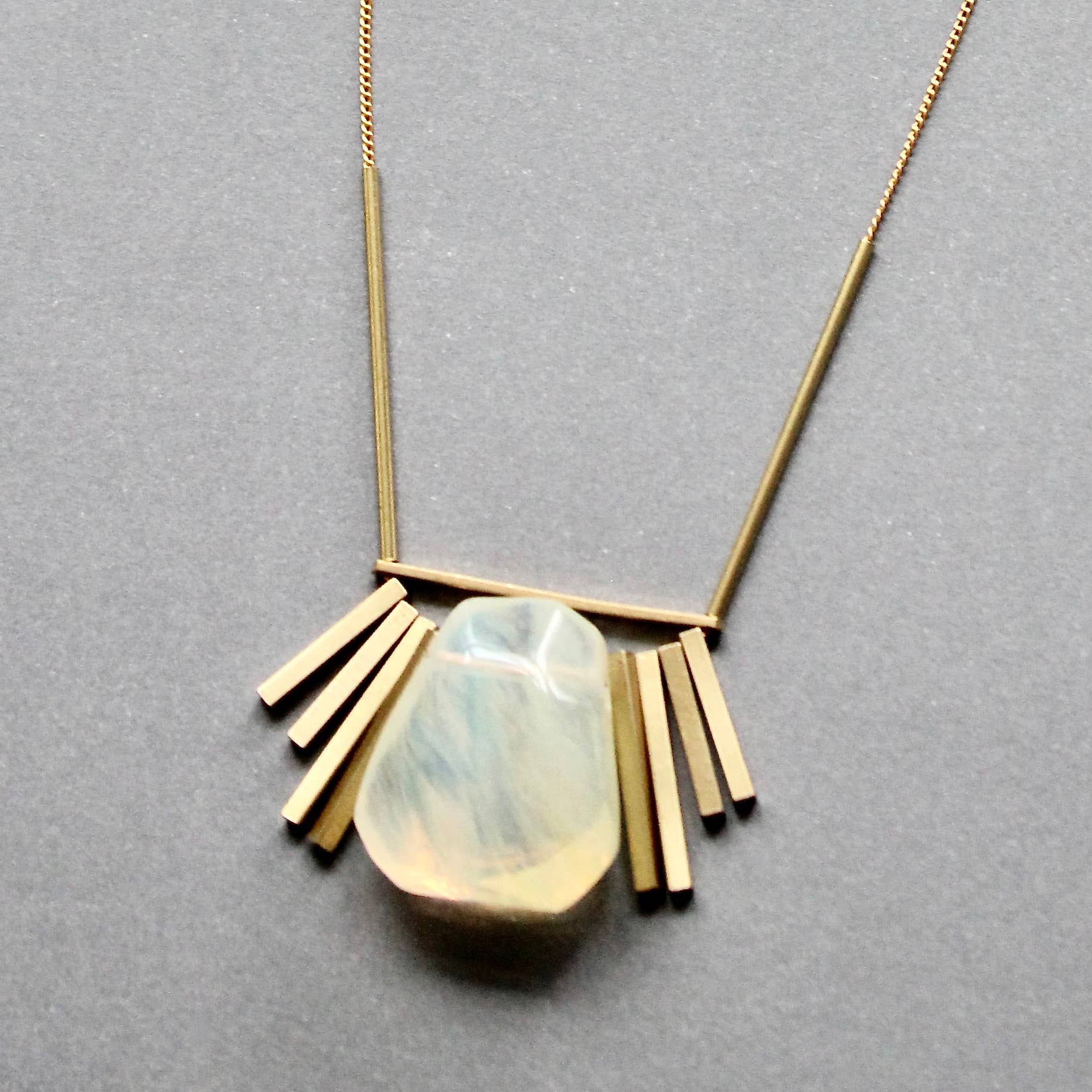 Necklace with a gold fringe and central stone on a gray background