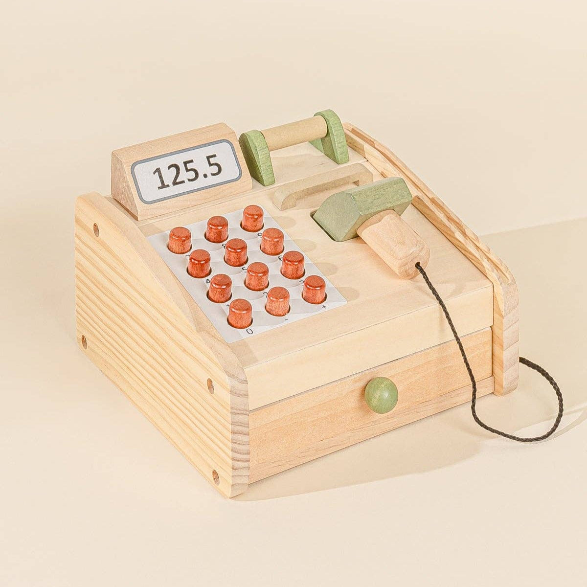 Wooden toy cash register with buttons and a display on a beige background