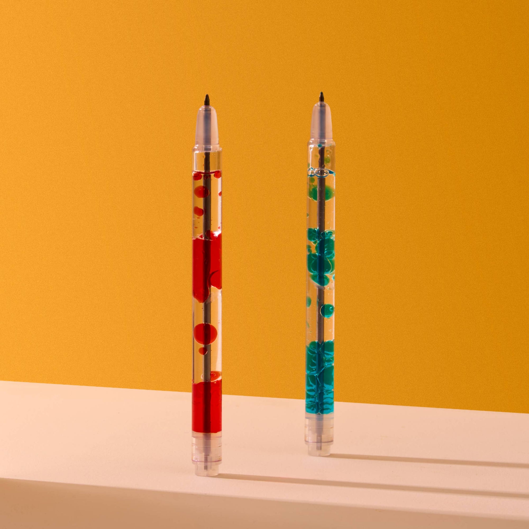 Two pens with colorful designs on a yellow and beige background