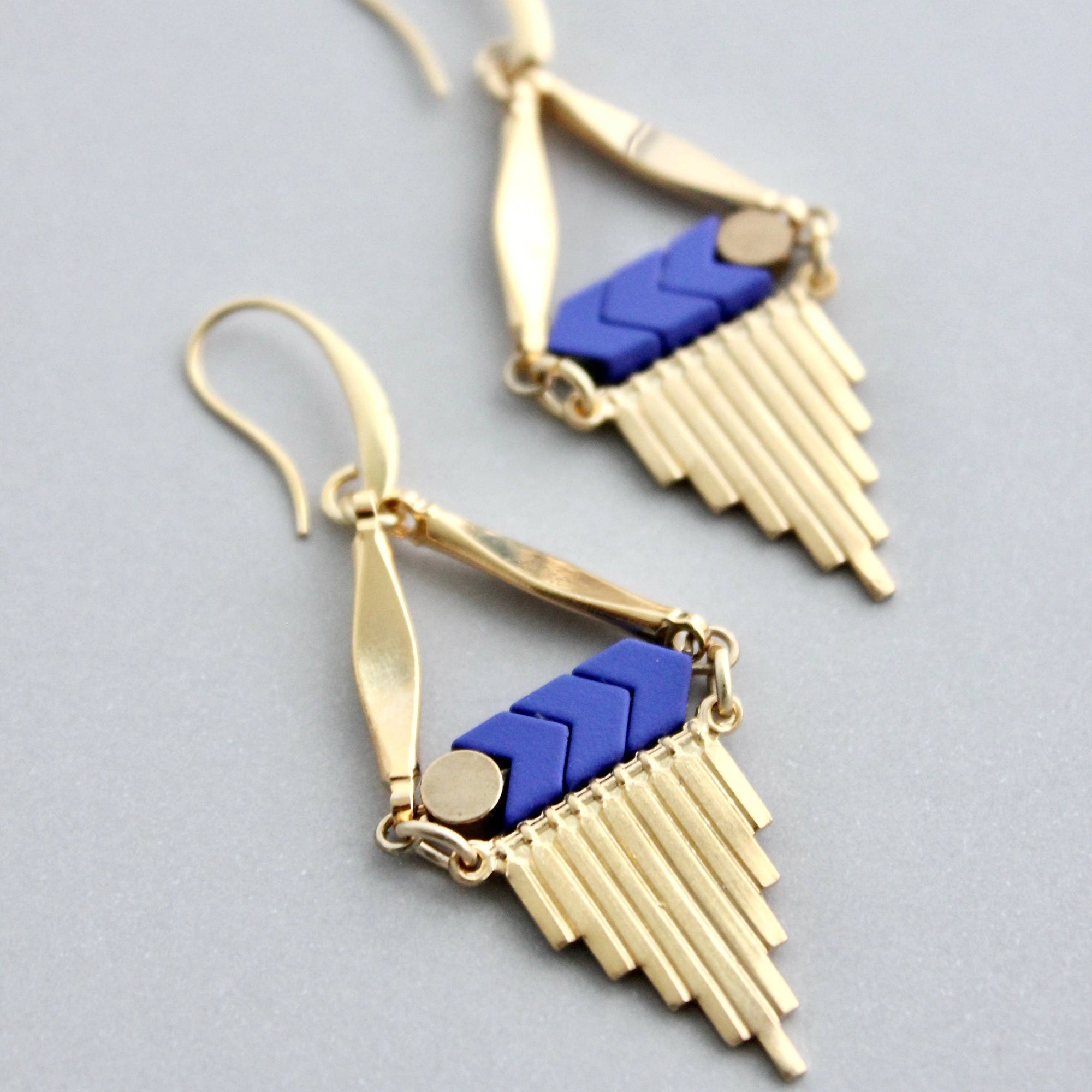 Gold and blue earrings on a gray background