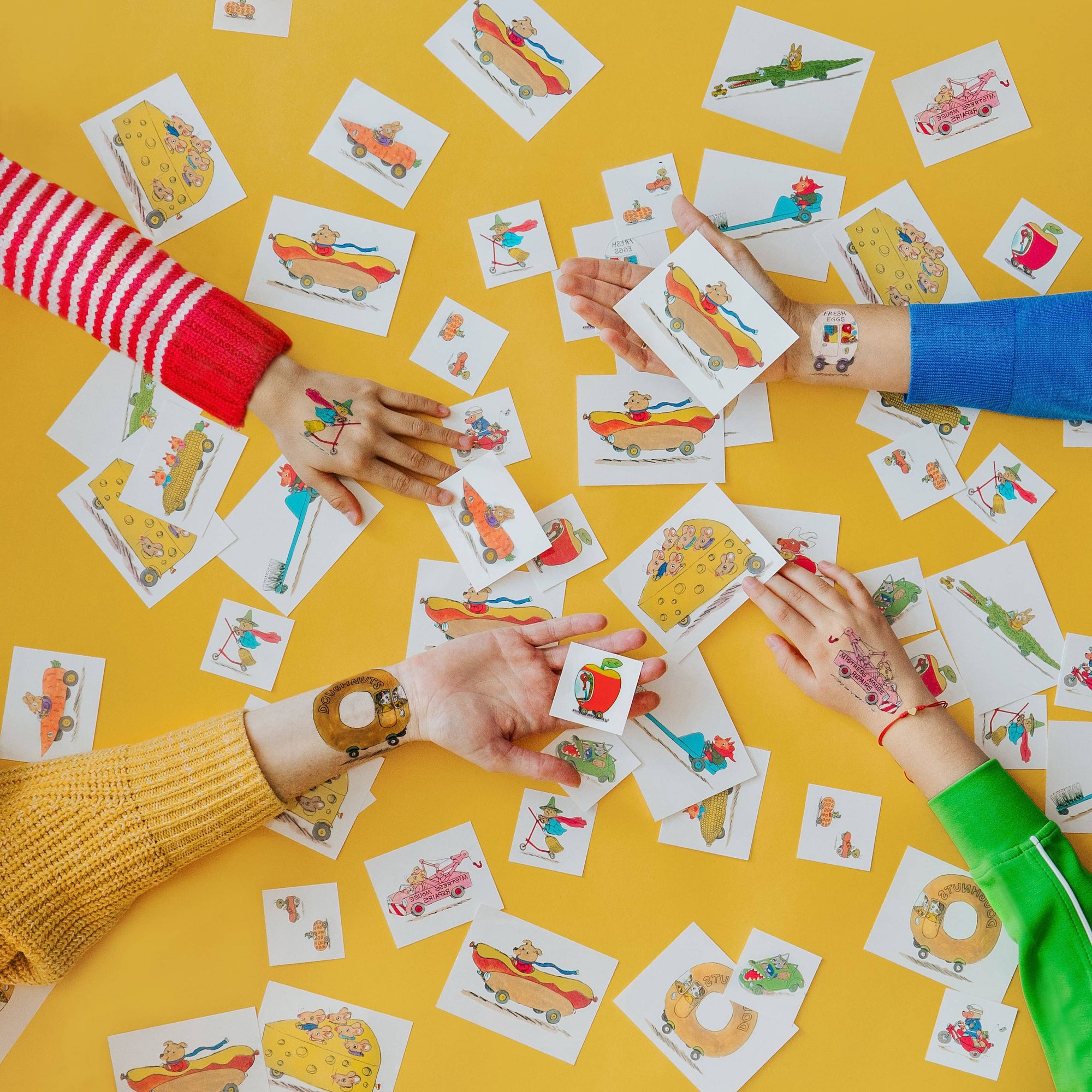 Children's hands playing with colorful cards on a yellow background
