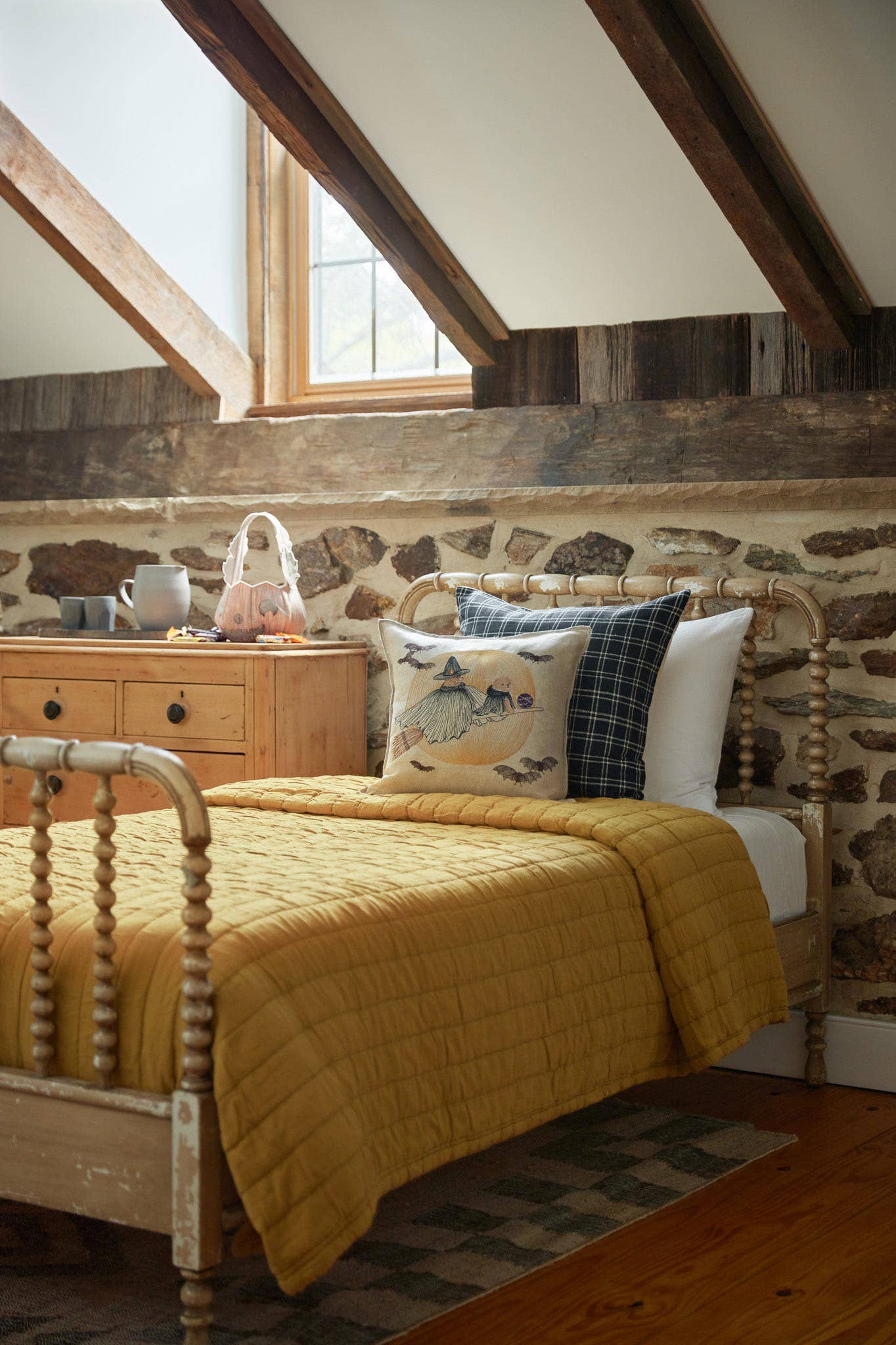 Bedroom with wooden bed, yellow quilt, and stone wall.