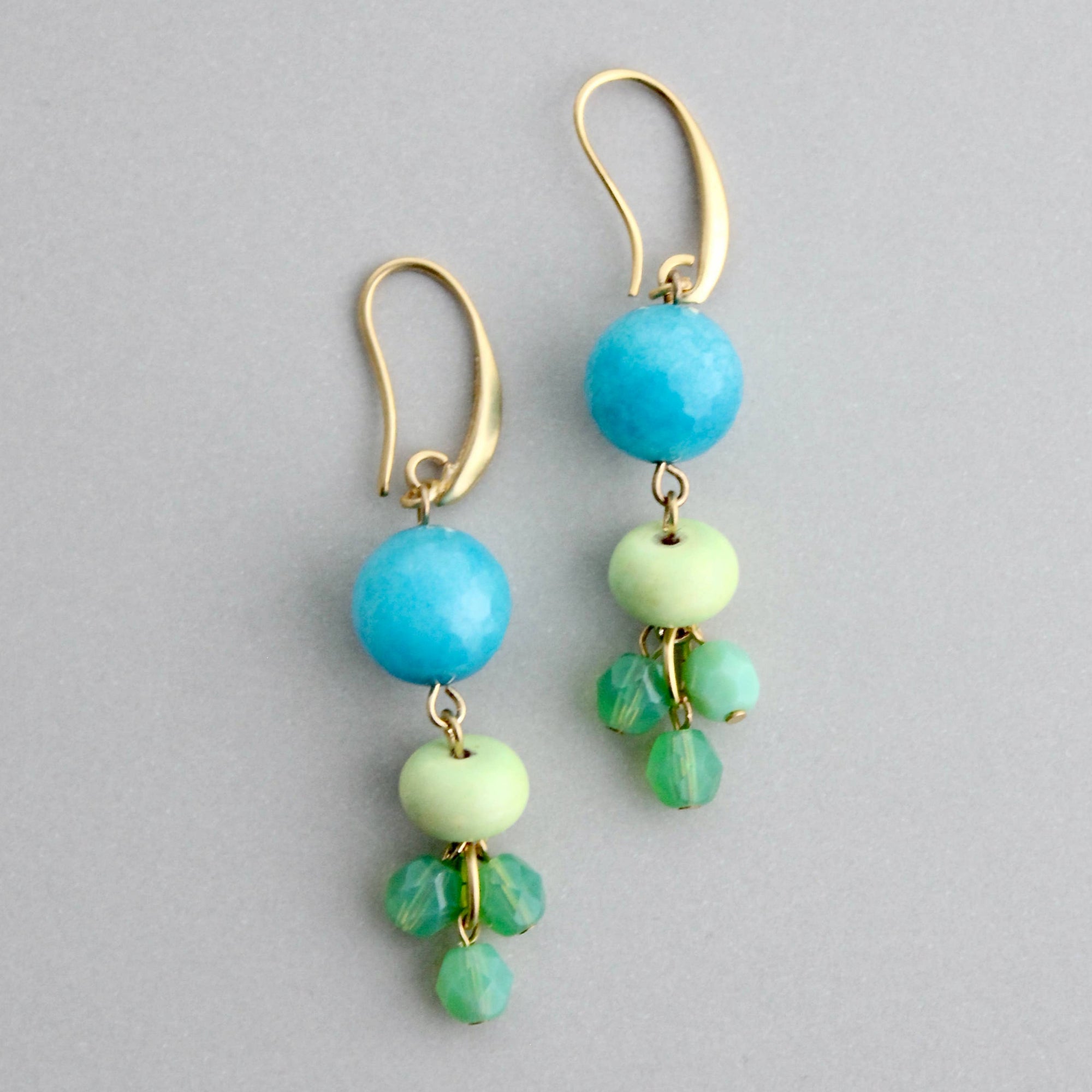 Pair of earrings with blue and green beads on a gray background
