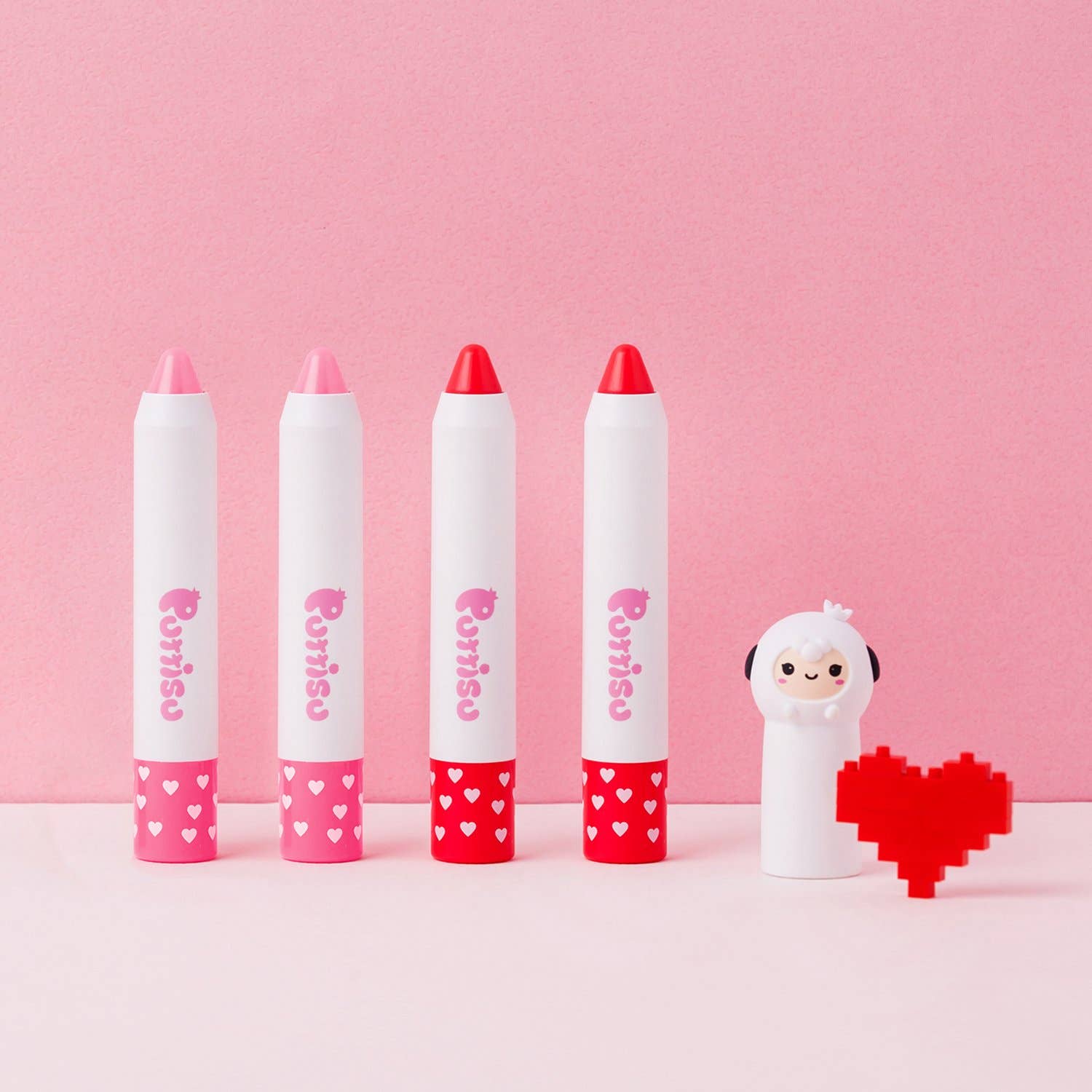 Five lip balms with red caps and heart designs on a pink background, accompanied by a small character and a pixelated heart.
