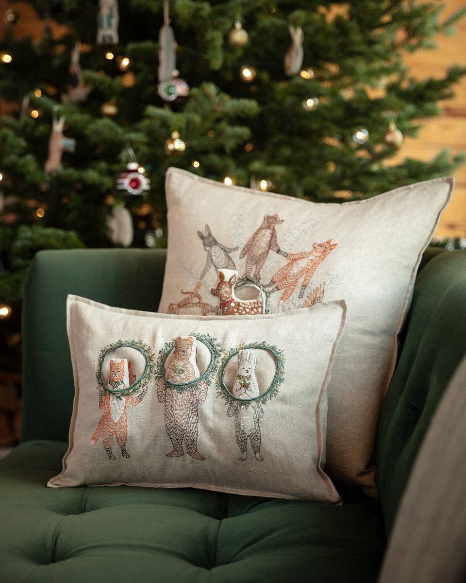 Decorative pillows with animal designs on a green couch in front of a Christmas tree.