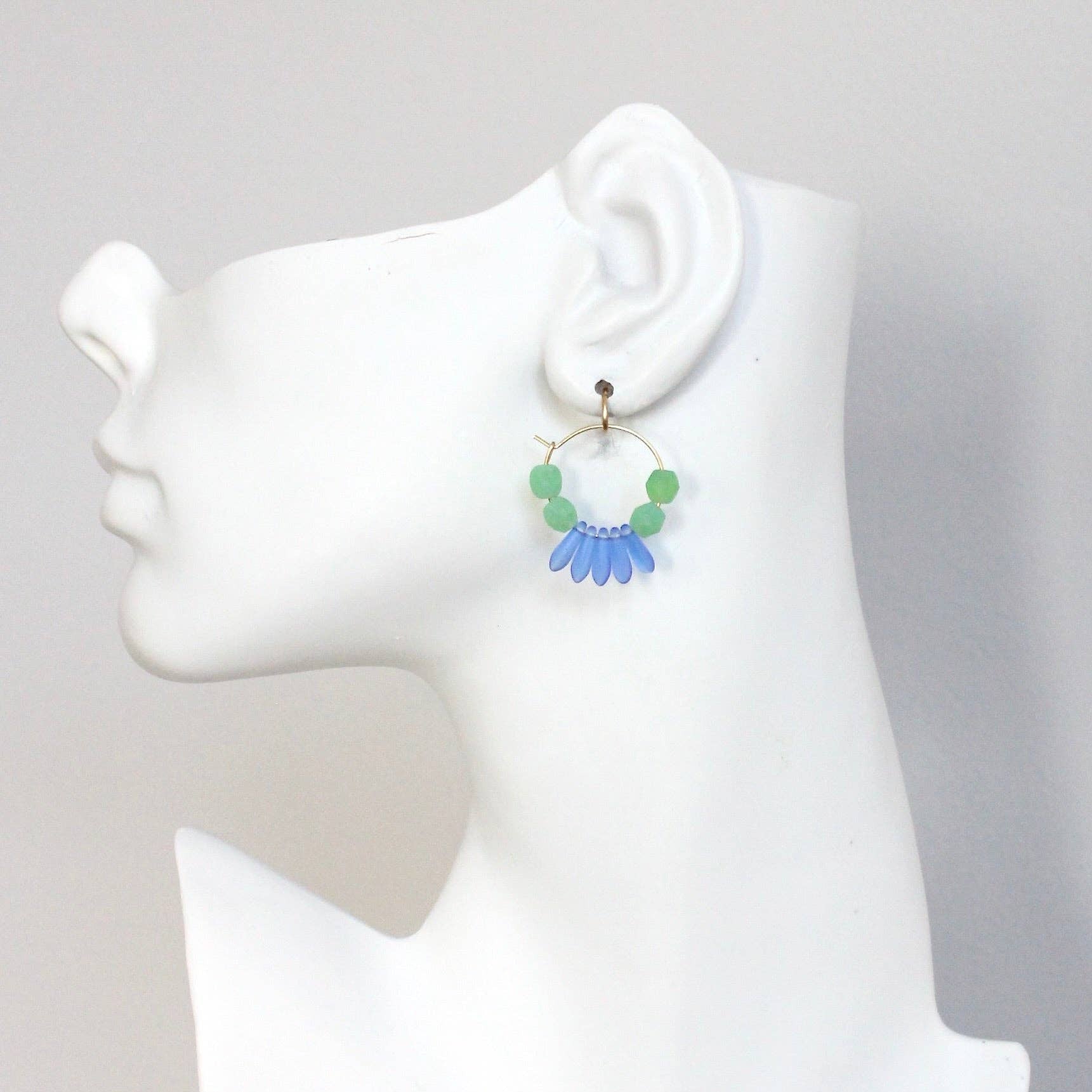 Earring displayed on a mannequin ear with a plain background
