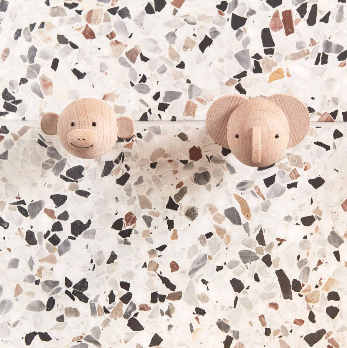 Two wooden toy elephants on a terrazzo-patterned surface