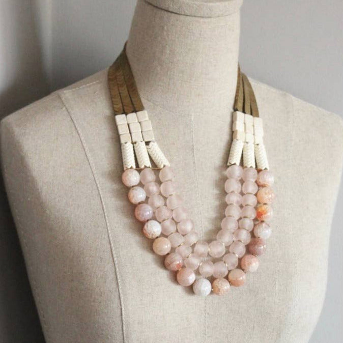 Necklace with pink and white beads on a mannequin against a neutral background