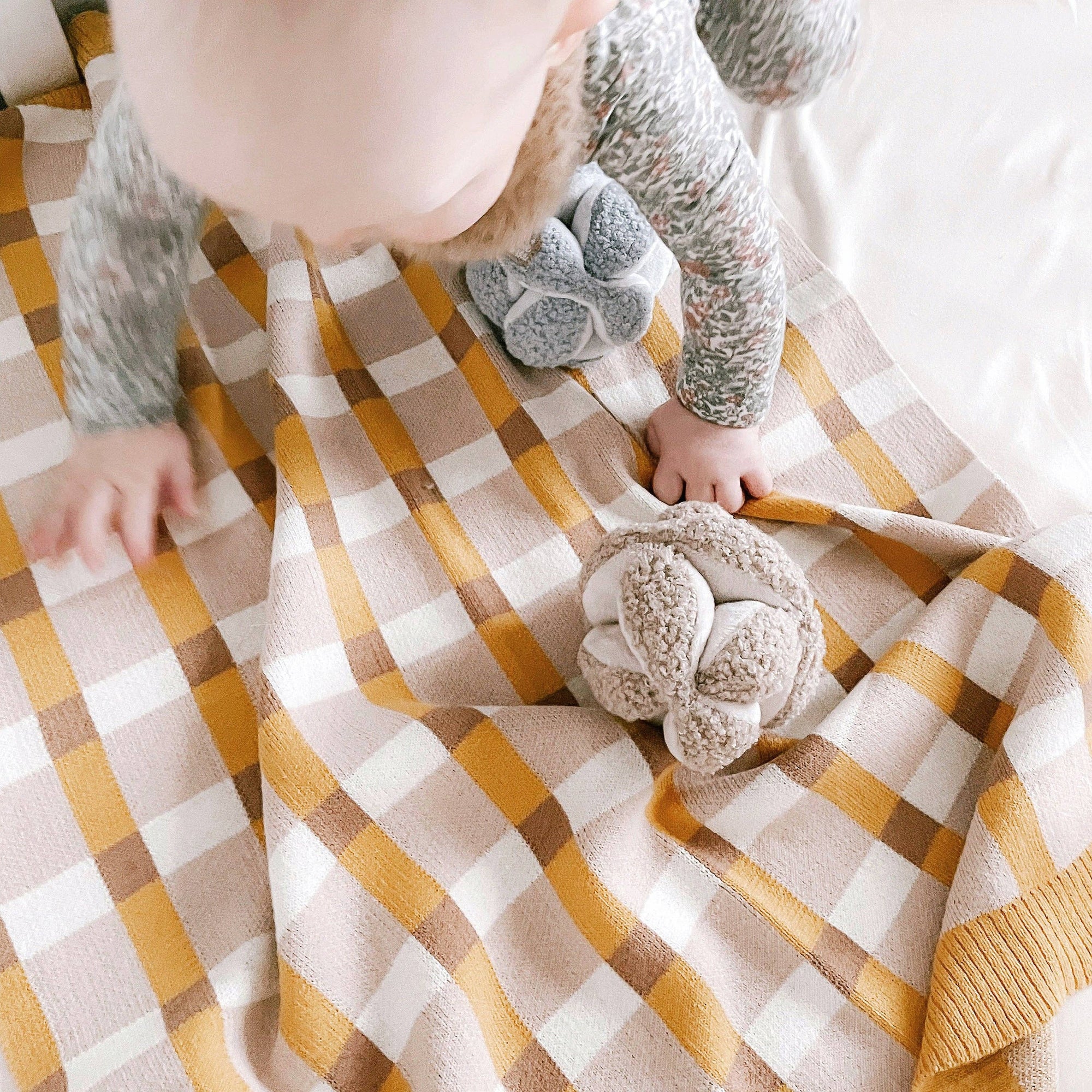 Child playing with a plush toy on a checkered blanket