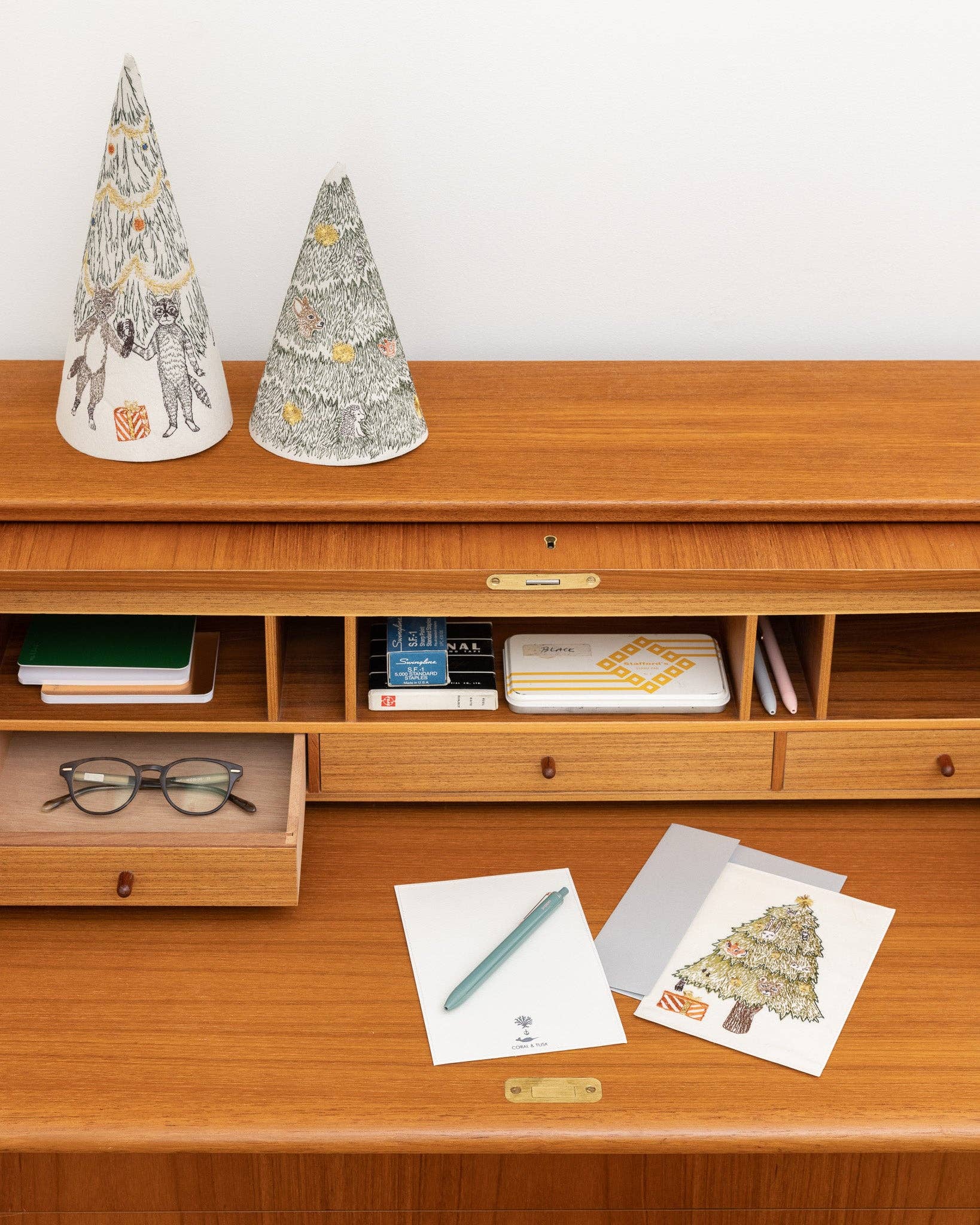 Wooden desk with decorative items, stationery, and a white wall background