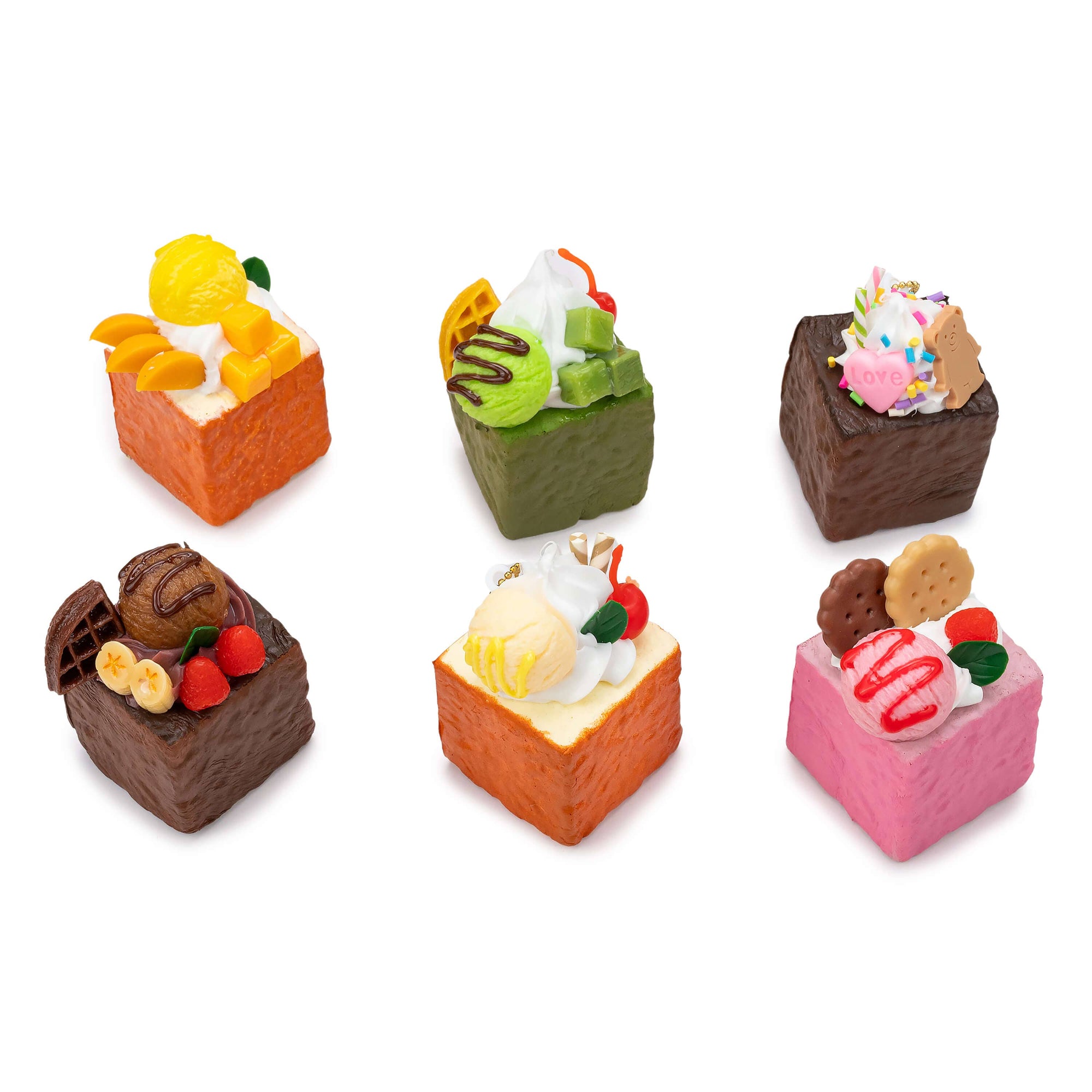 Set of small square toy desserts with various toppings on a white background